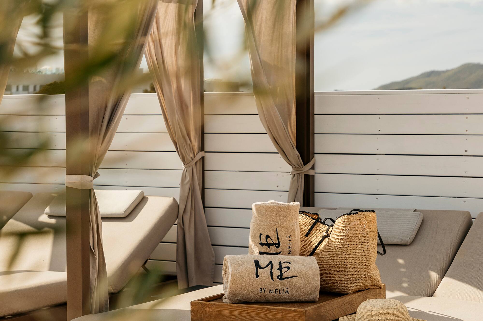 Outdoor daybed with 'ME by Melia' towels, straw bag, hat, espadrilles.
