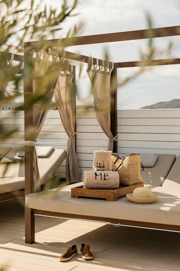 a lounge chair with a hat and bags on it