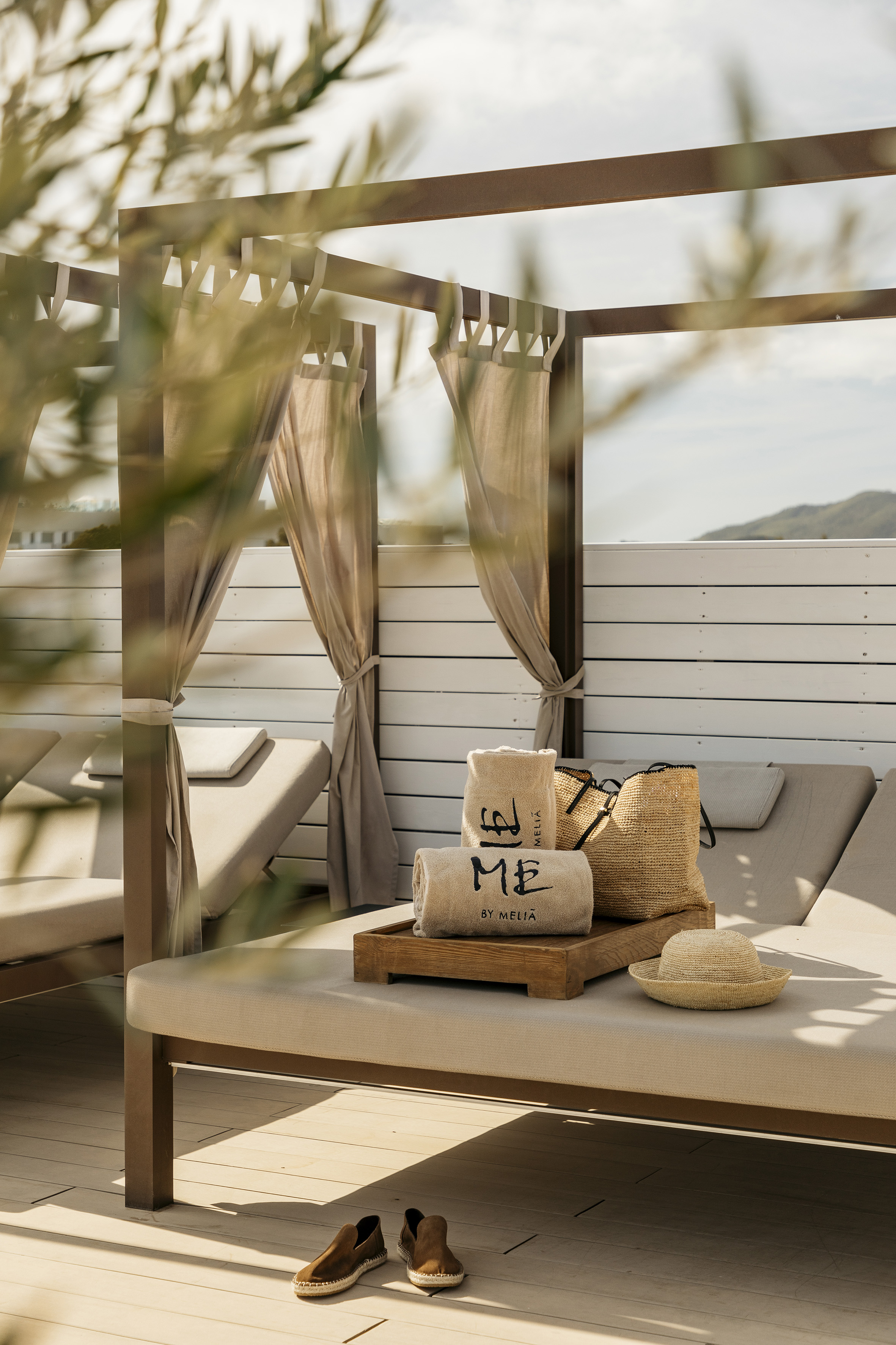 Outdoor daybed with 'ME by Melia' towels, straw bag, hat, espadrilles.