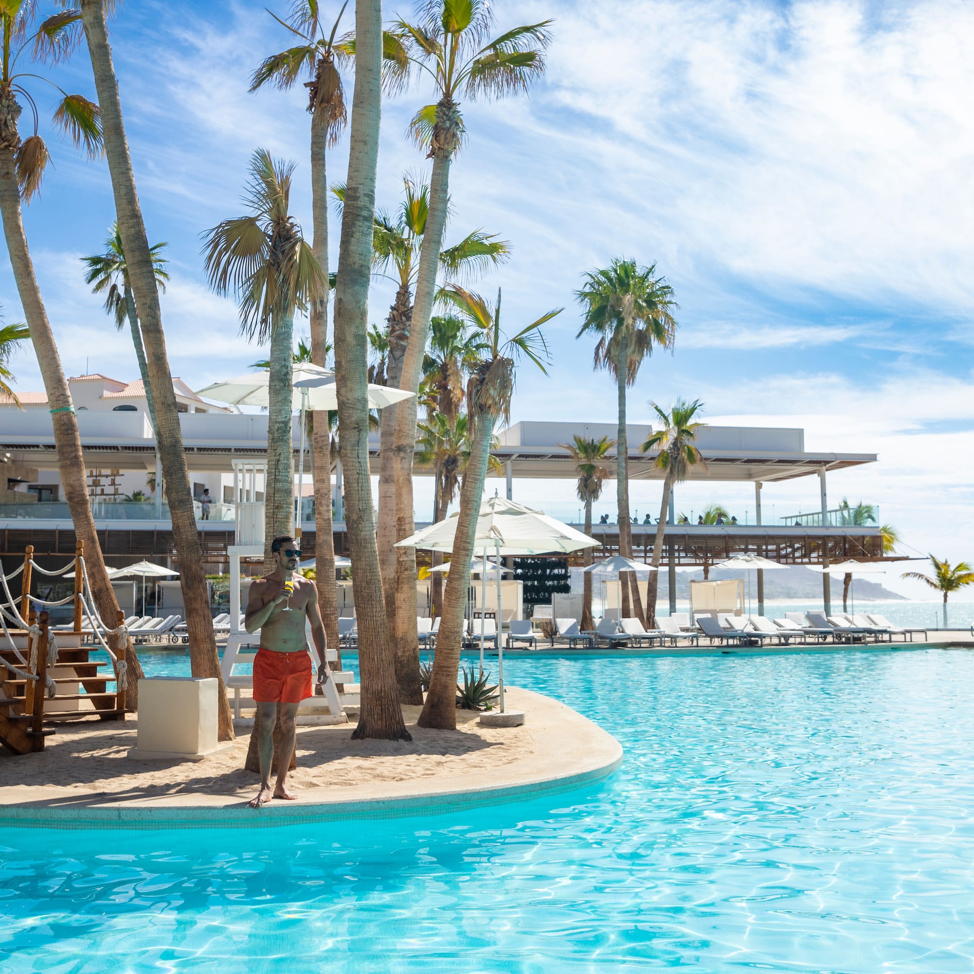 a man standing in a pool with palm trees