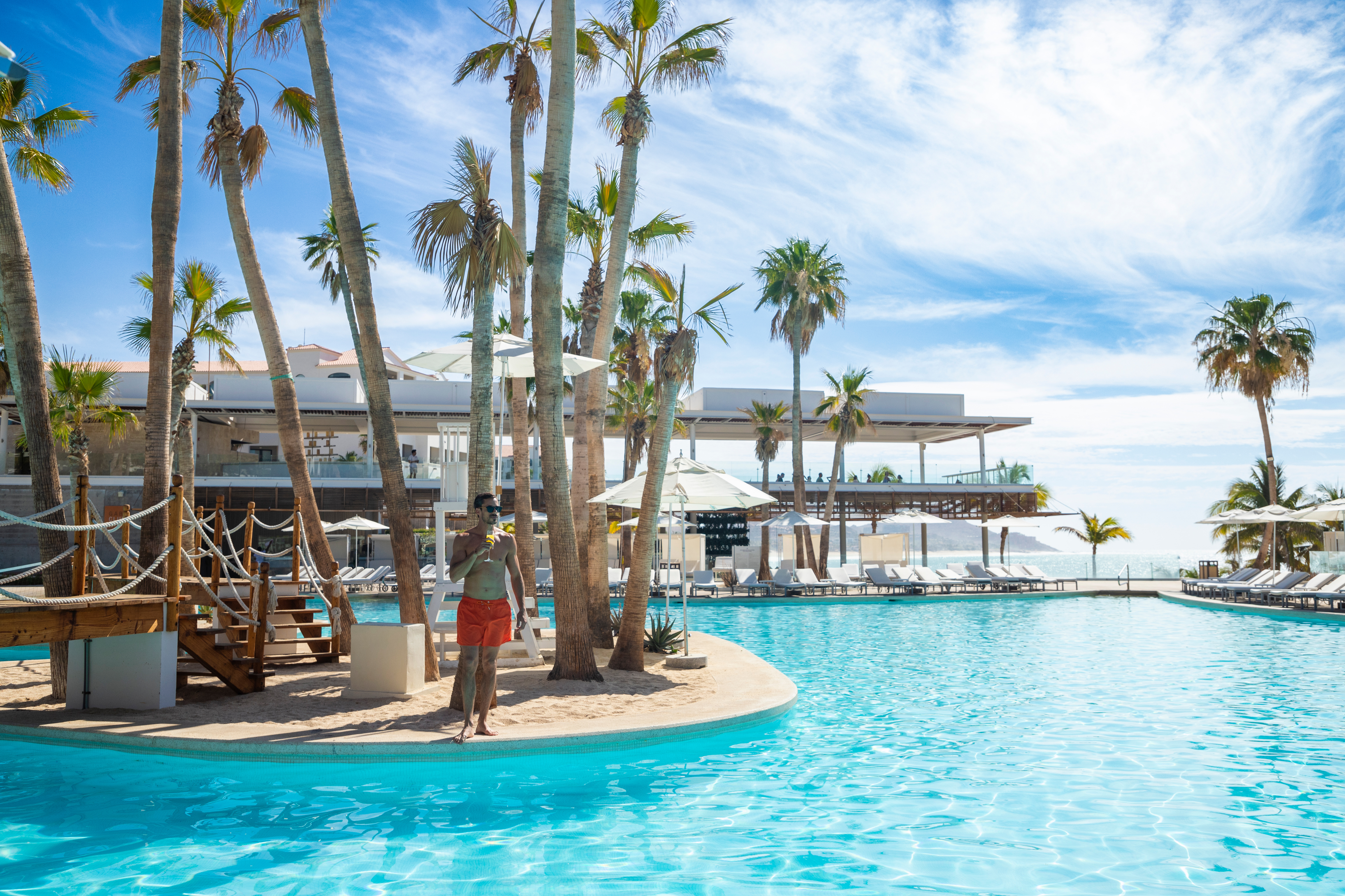 a man standing in a pool with palm trees