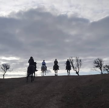 a group of people riding horses on a dirt hill