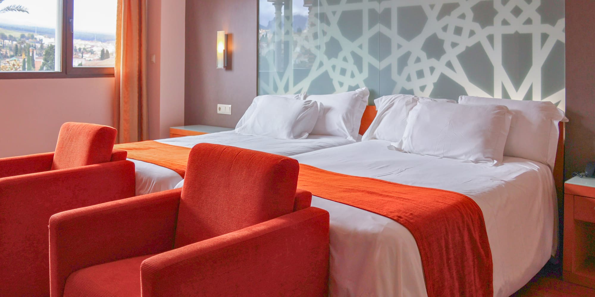 a room with two beds and red chairs