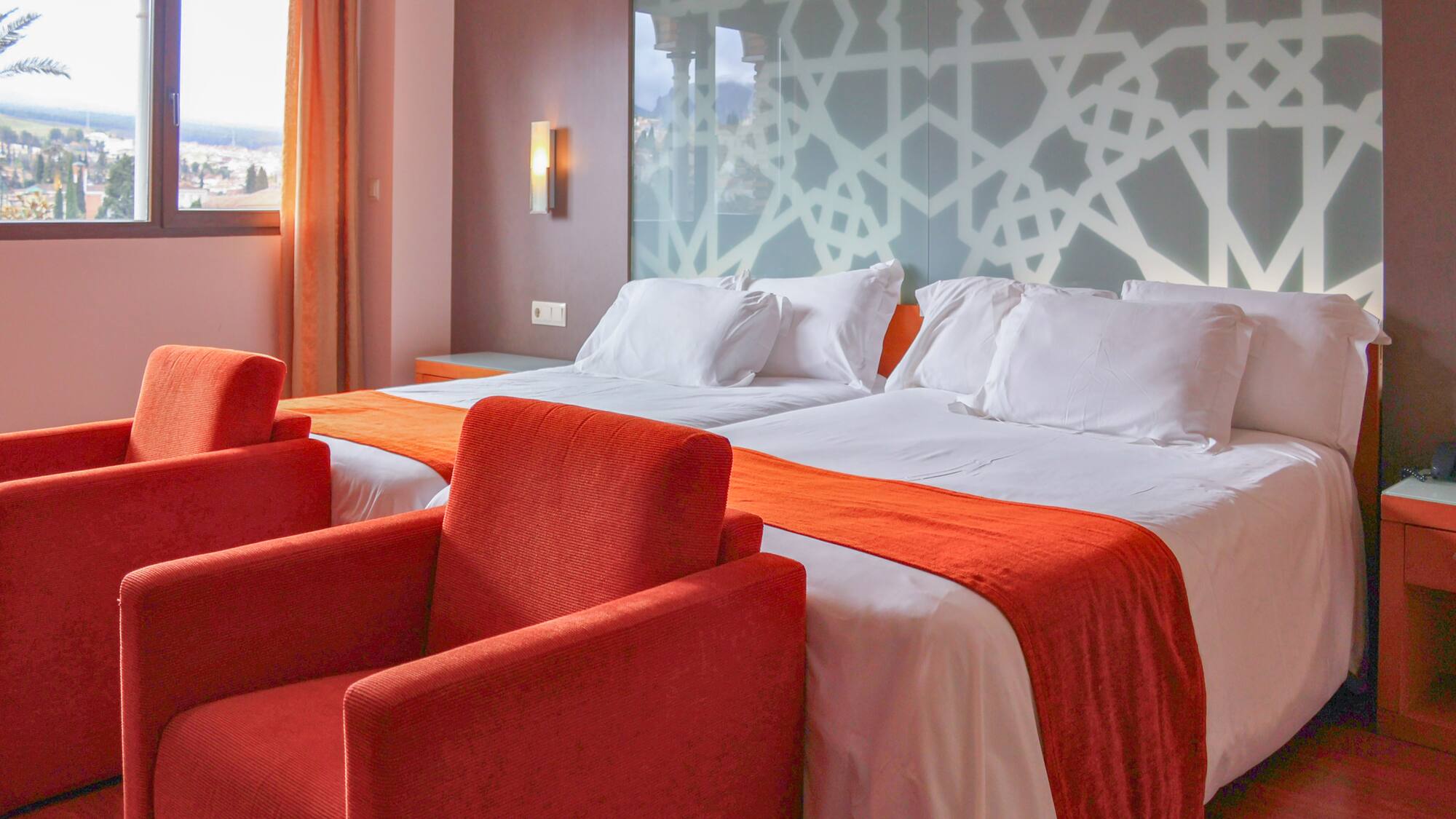 a room with two beds and red chairs