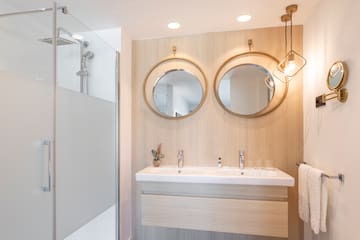 a bathroom with a shower and two mirrors