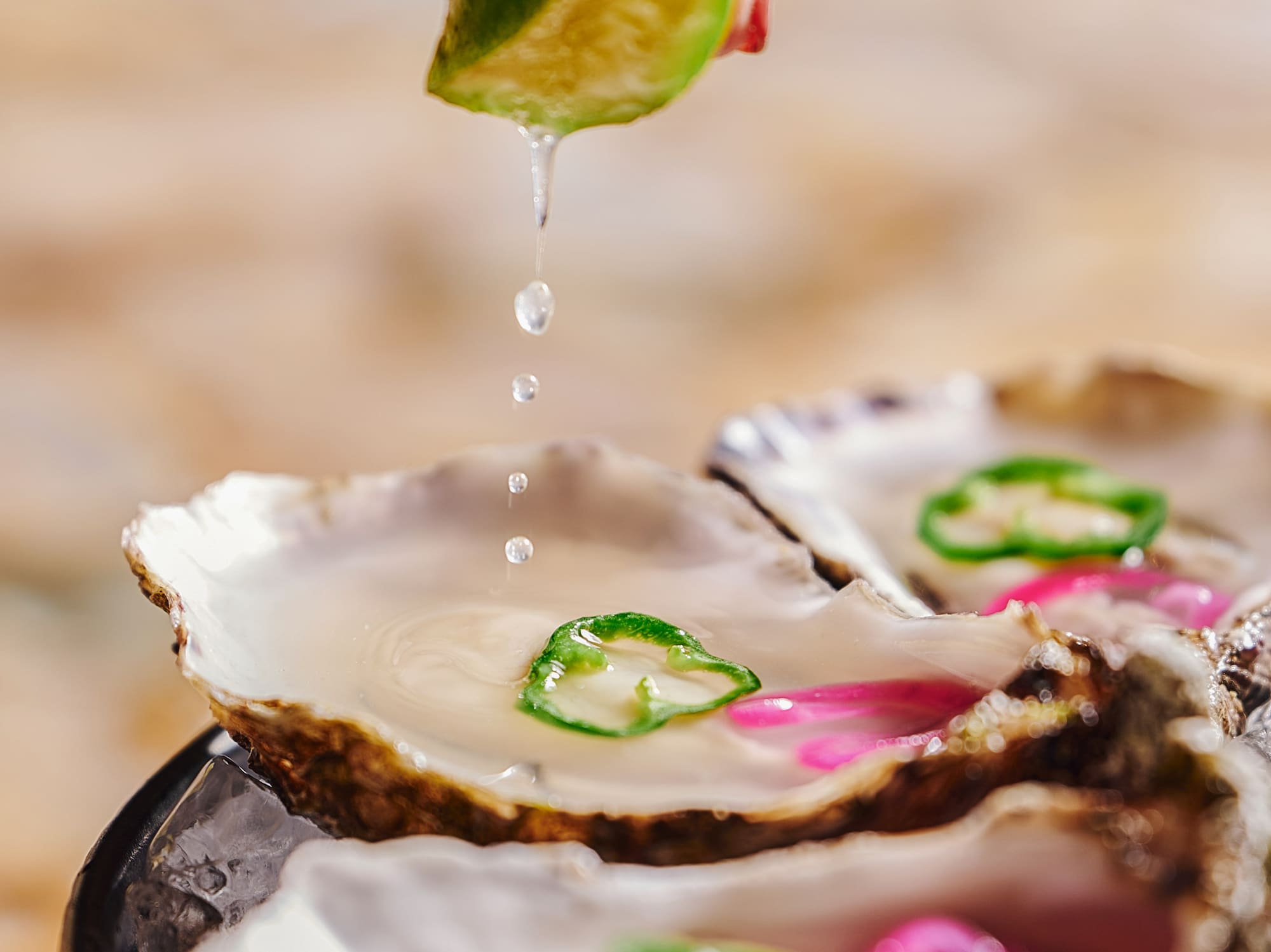 a person pouring a lime over oysters