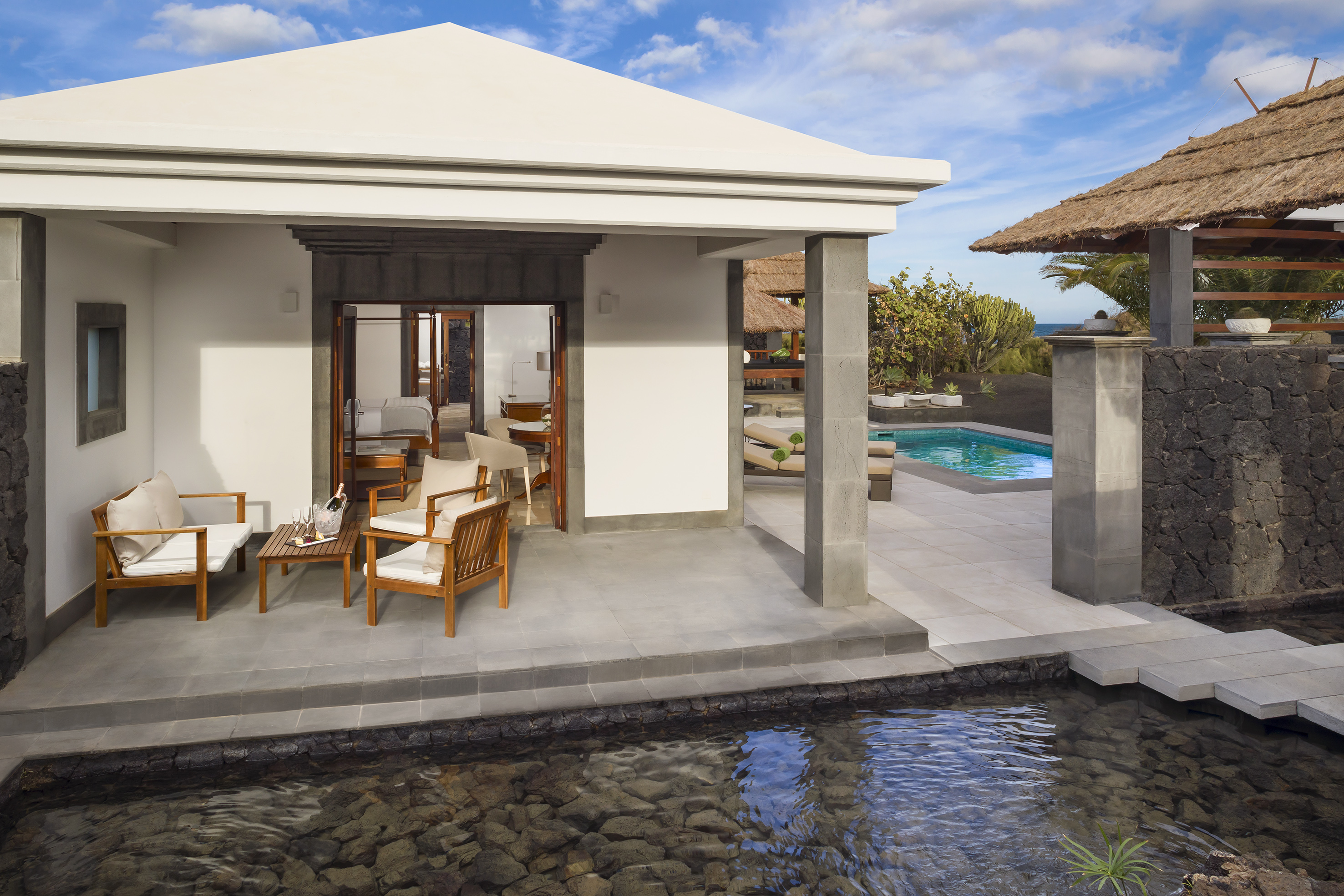 Luxury resort villa patio with outdoor seating, private pool, and water garden.