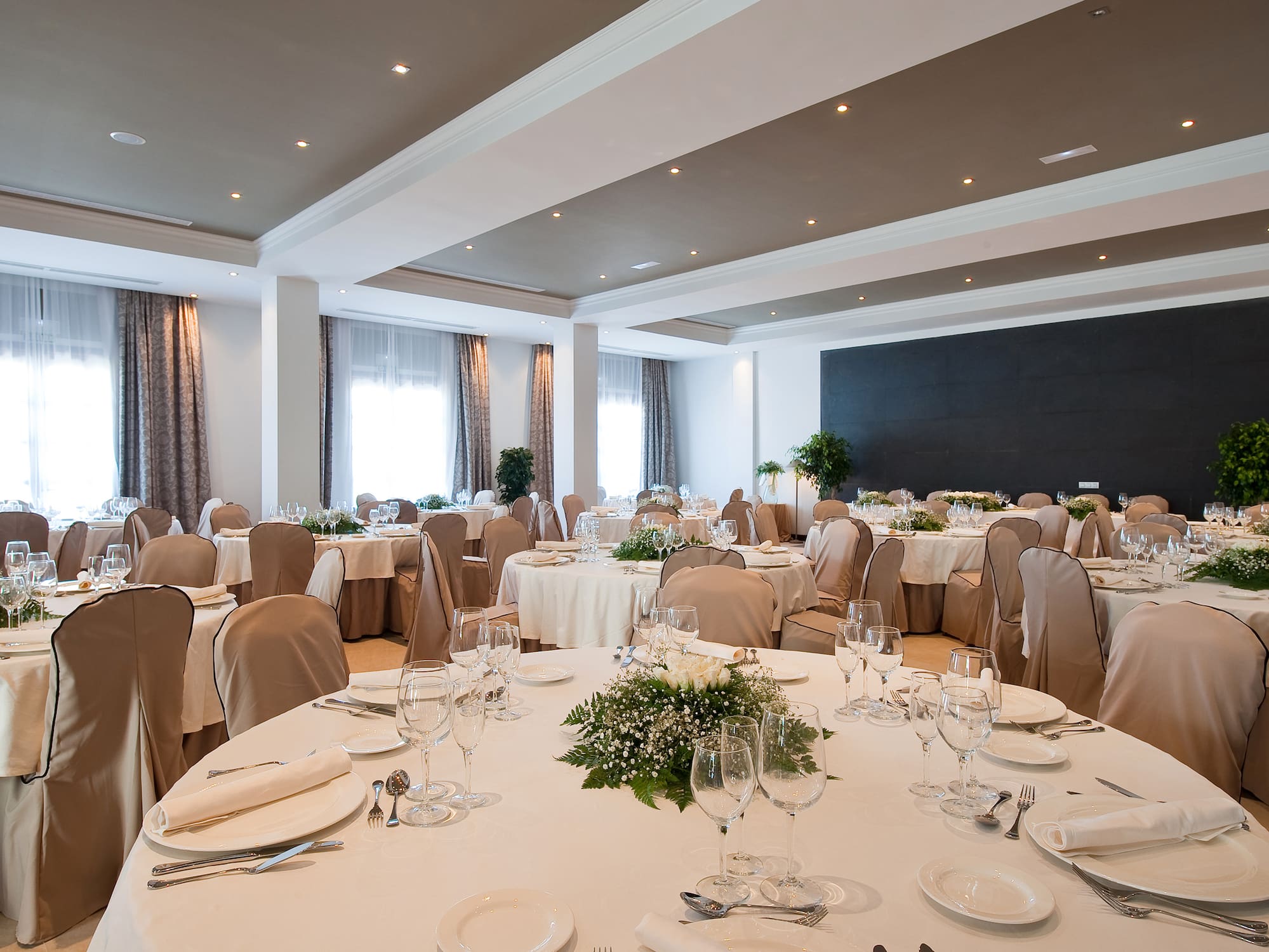 Elegant reception hall with dining tables, white linens, and floral centerpieces.