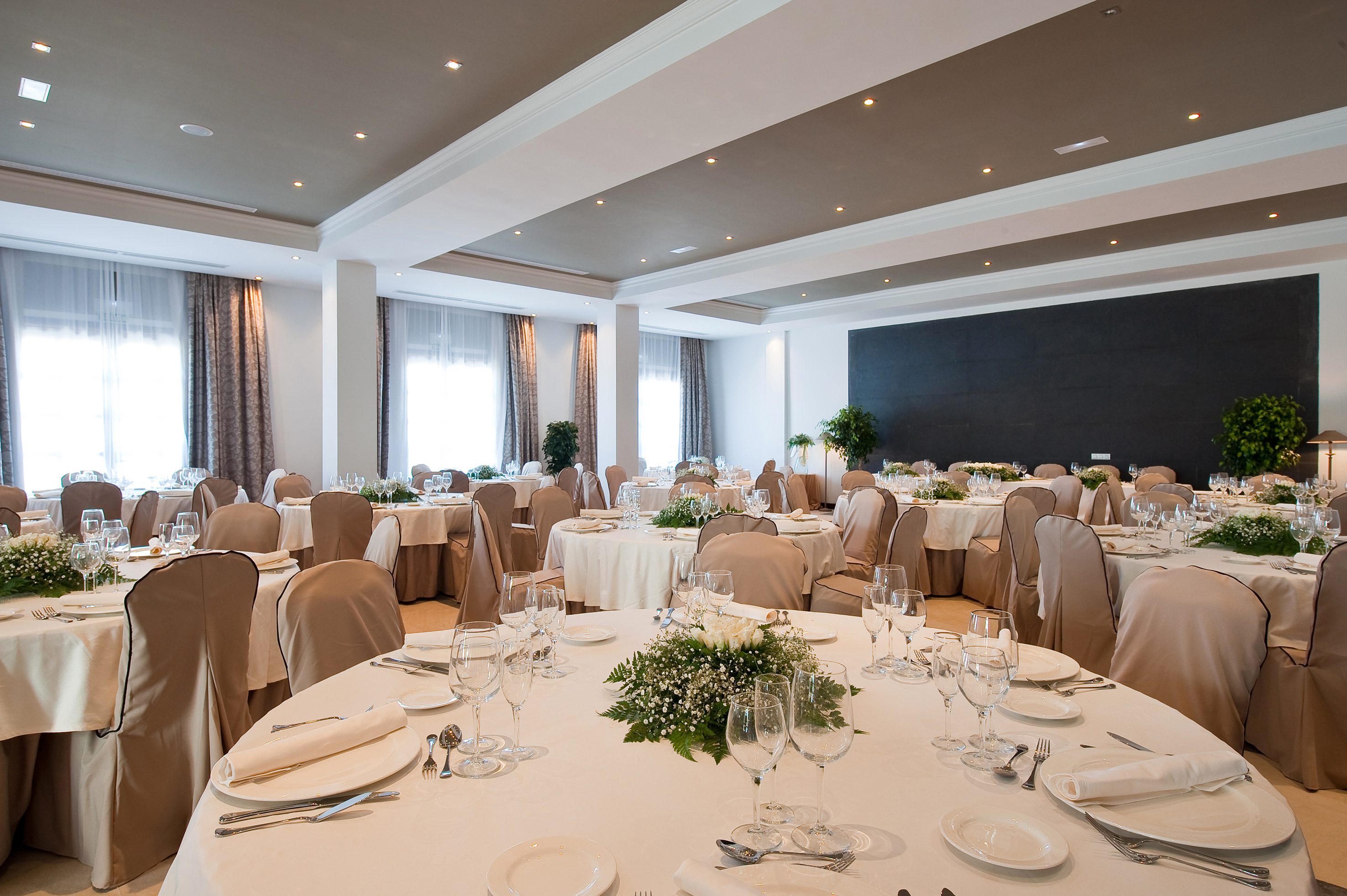 Elegant reception hall with dining tables, white linens, and floral centerpieces.