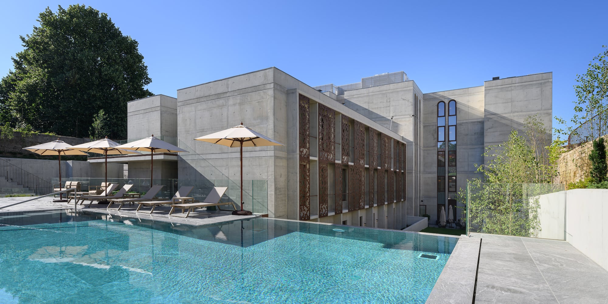 a pool with umbrellas and chairs in front of a building