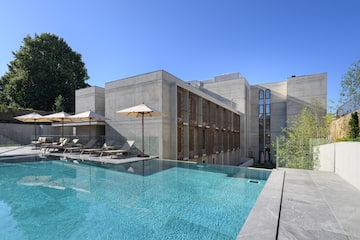 a pool with umbrellas and chairs in front of a building