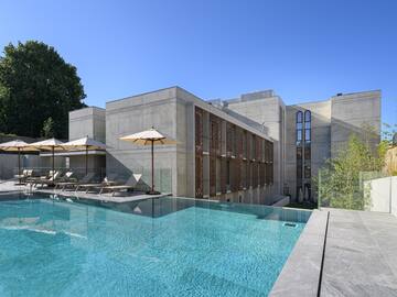 a pool with umbrellas and chairs in front of a building