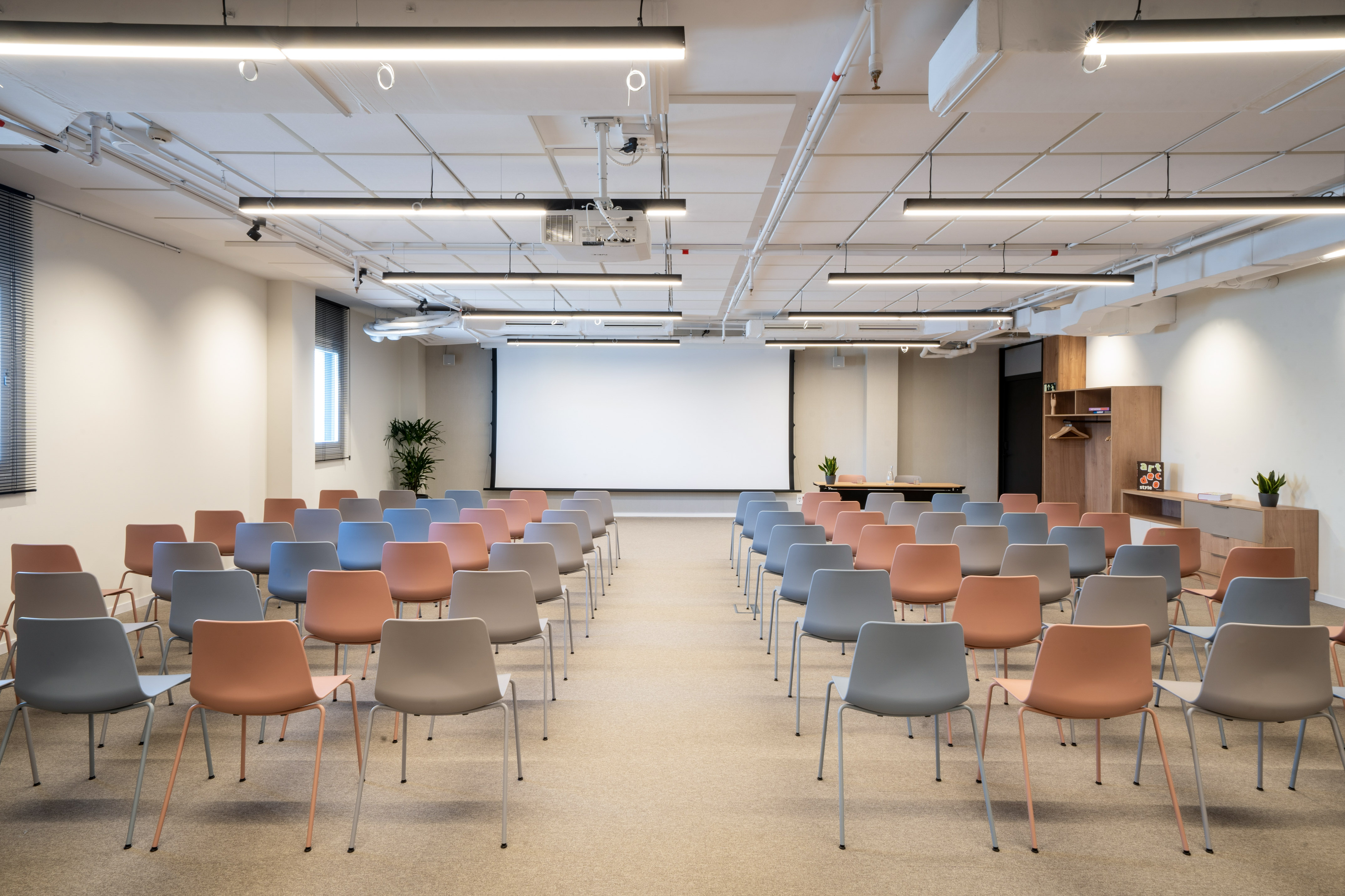 Modern conference room with colorful chairs, big screen, and overhead projector.