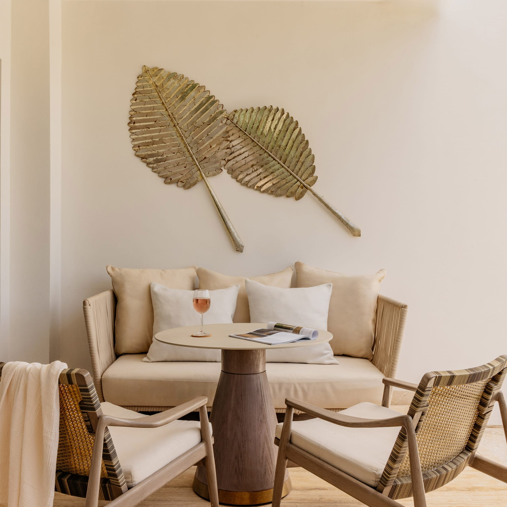 Tropical patio with lounge furniture, table, and gold leaf wall art.
