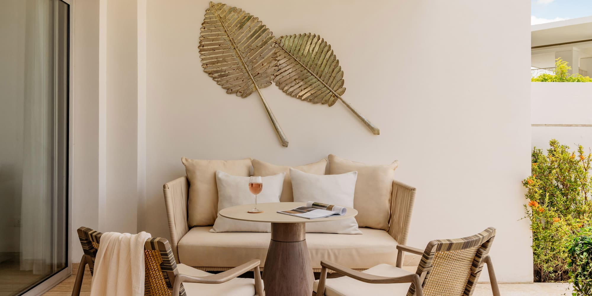 Tropical patio with lounge furniture, table, and gold leaf wall art.