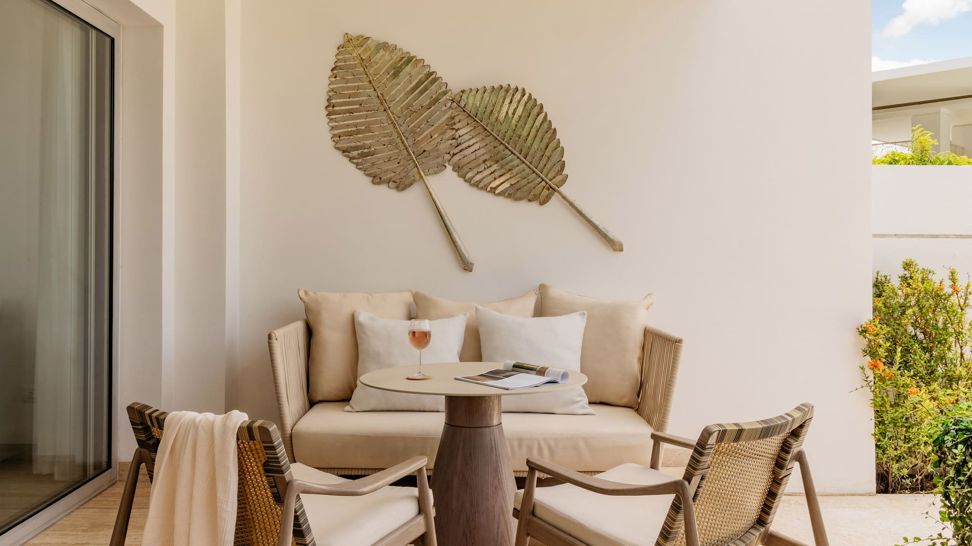 Tropical patio with lounge furniture, table, and gold leaf wall art.
