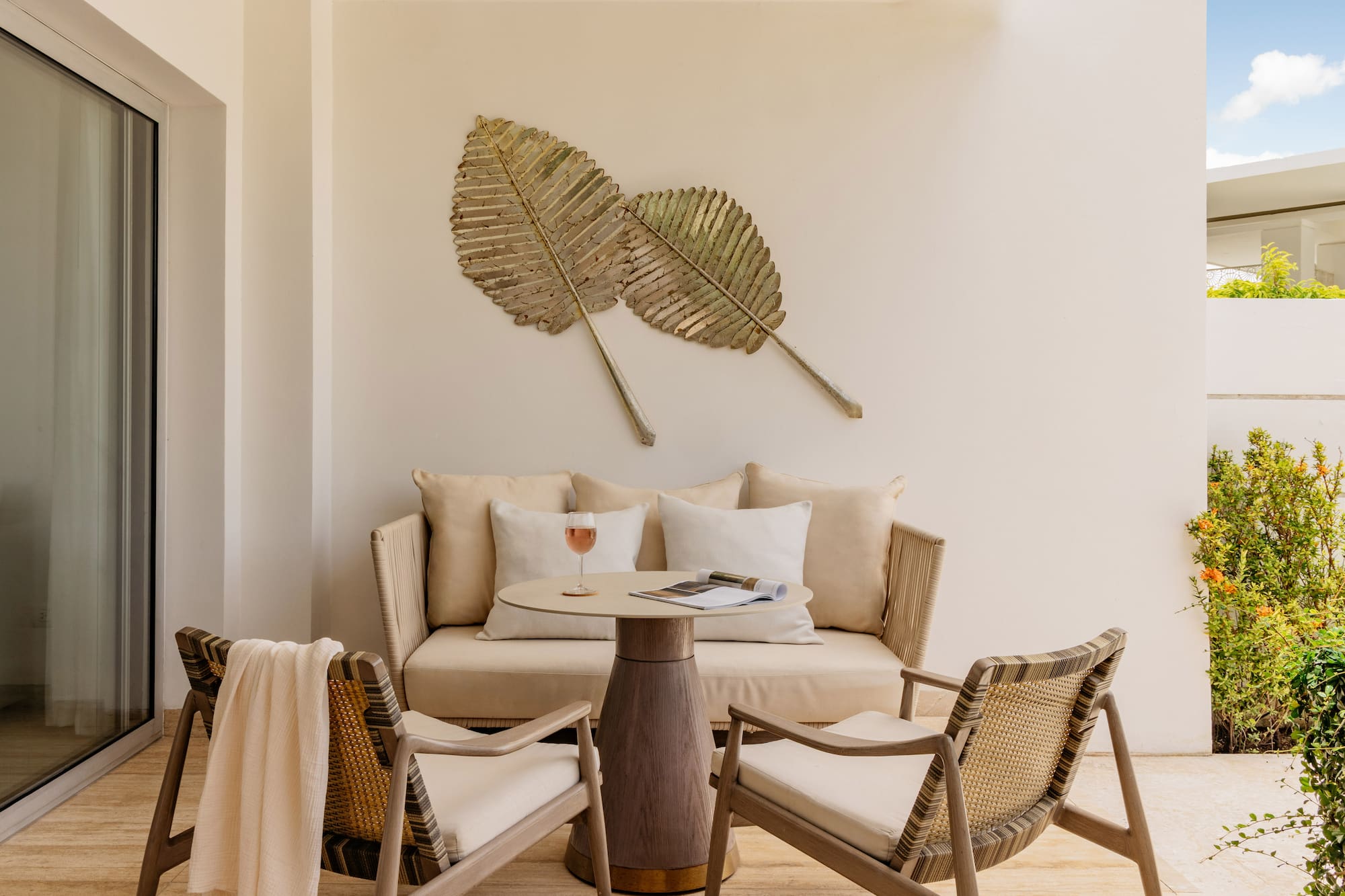 Tropical patio with lounge furniture, table, and gold leaf wall art.