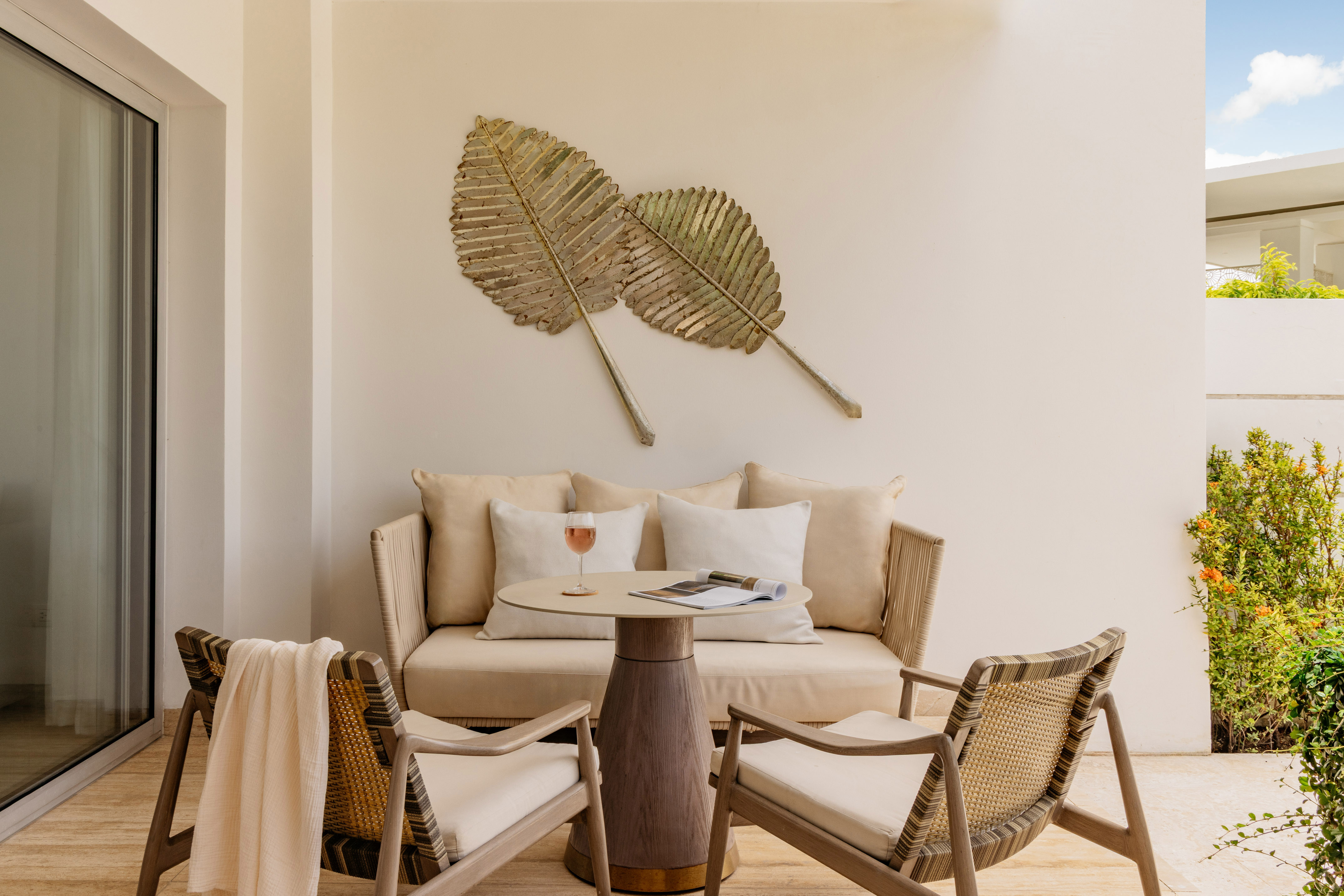 Tropical patio with lounge furniture, table, and gold leaf wall art.