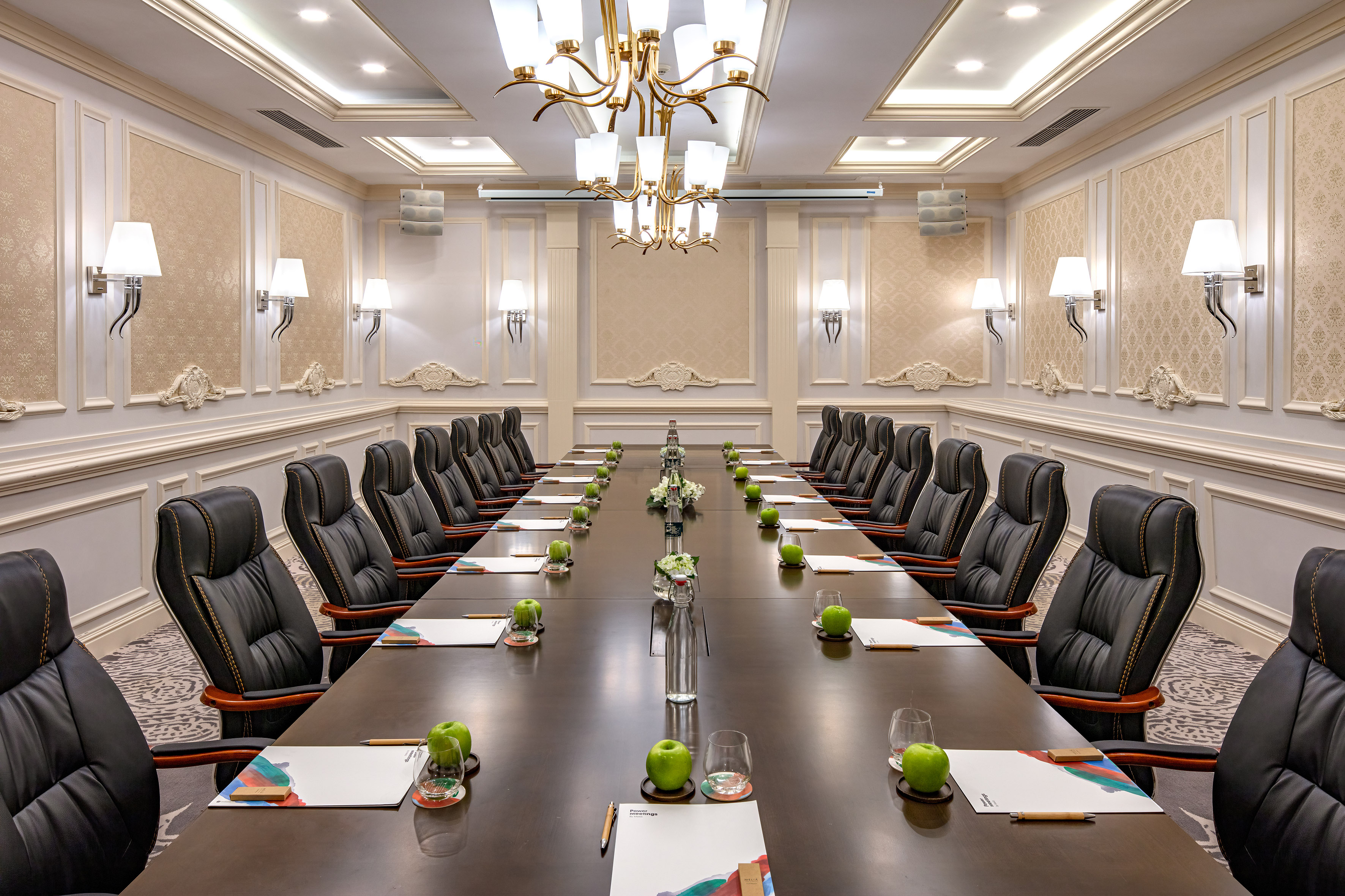 Elegant boardroom with long table, leather executive chairs, chandelier.
