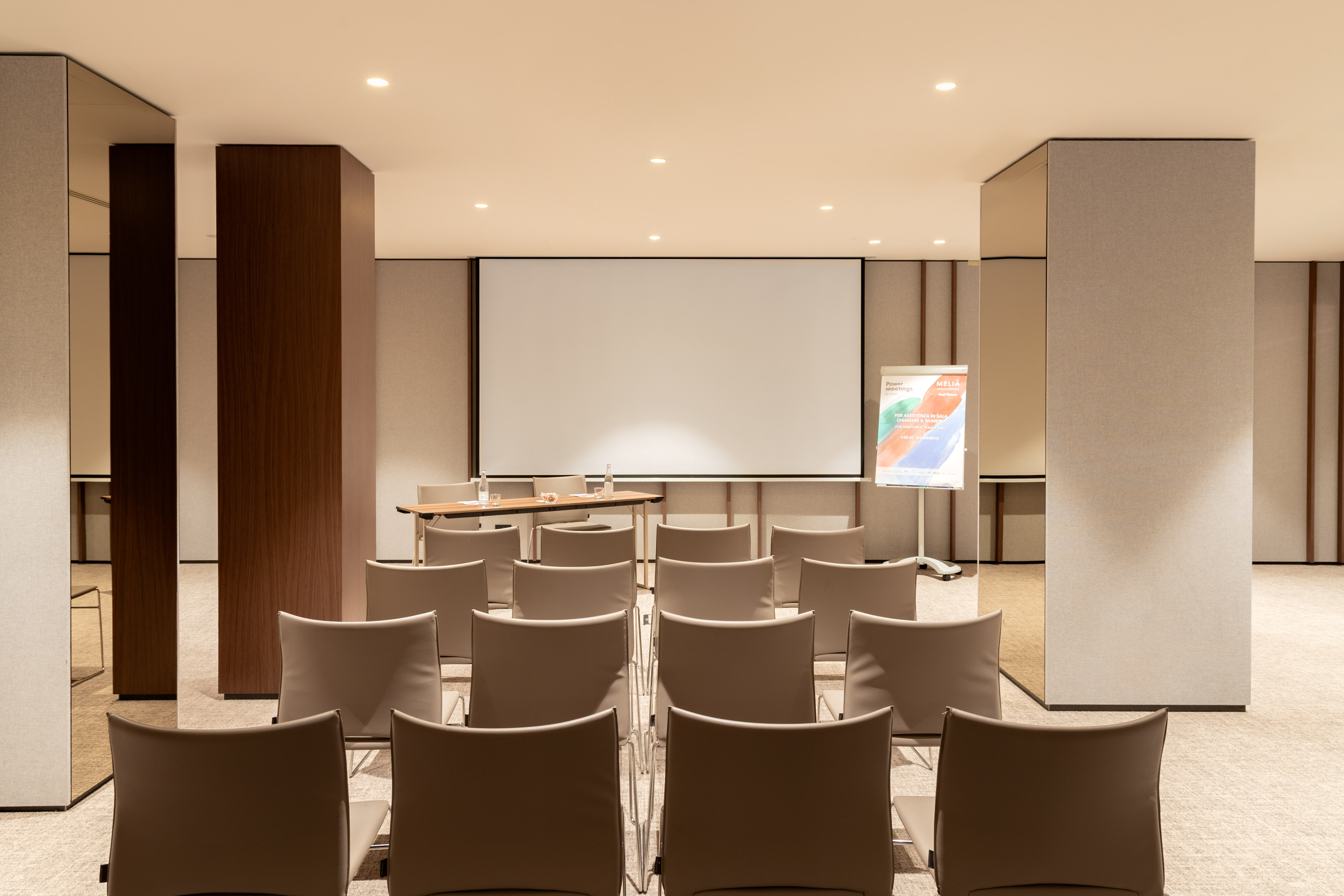 Modern corporate meeting room with projection screen, chairs, and table.