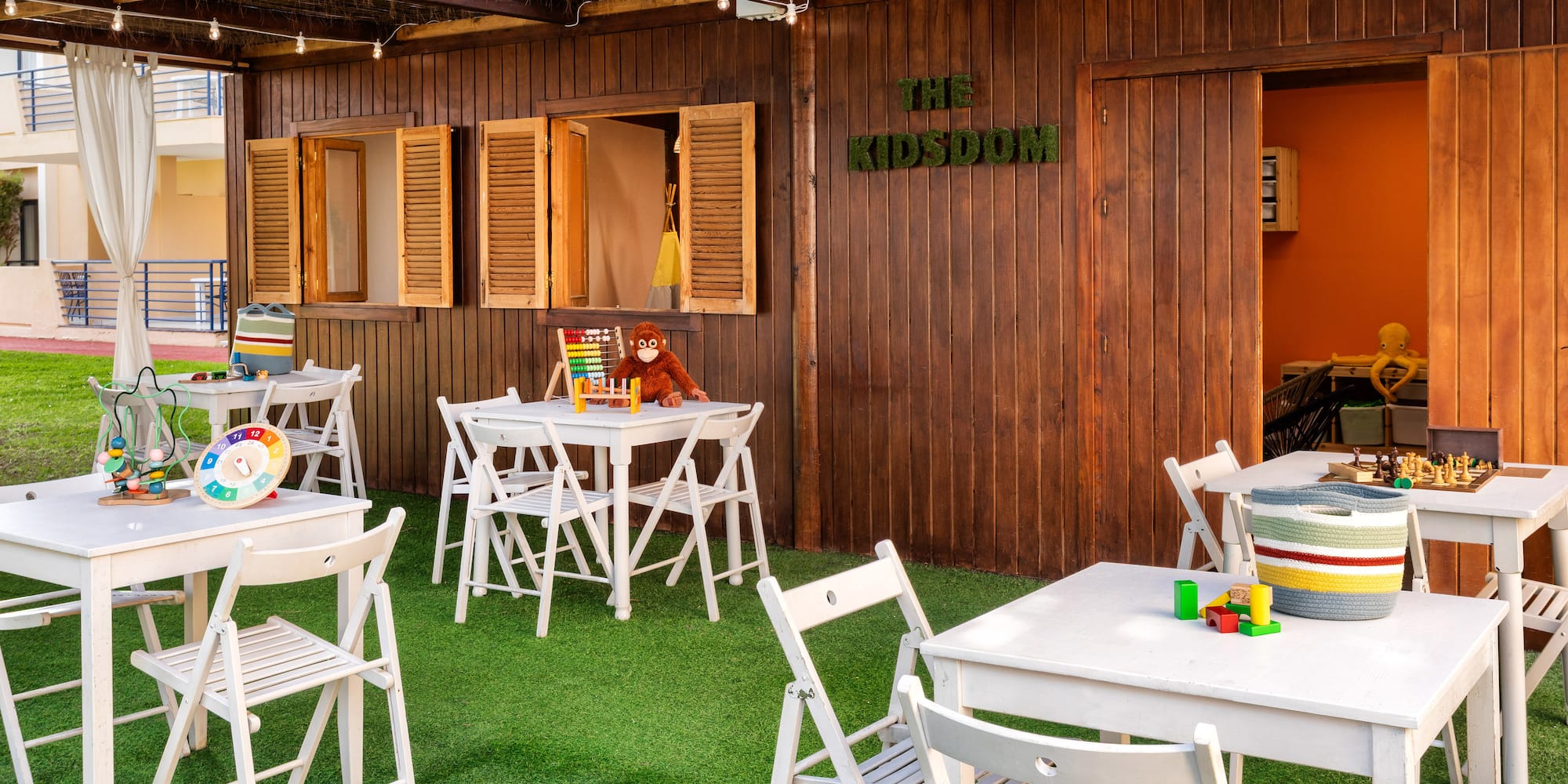 a small outdoor restaurant with white tables and chairs