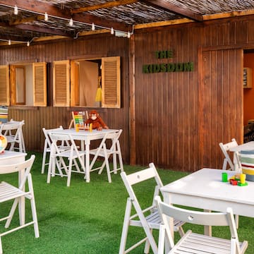 a small outdoor restaurant with white tables and chairs