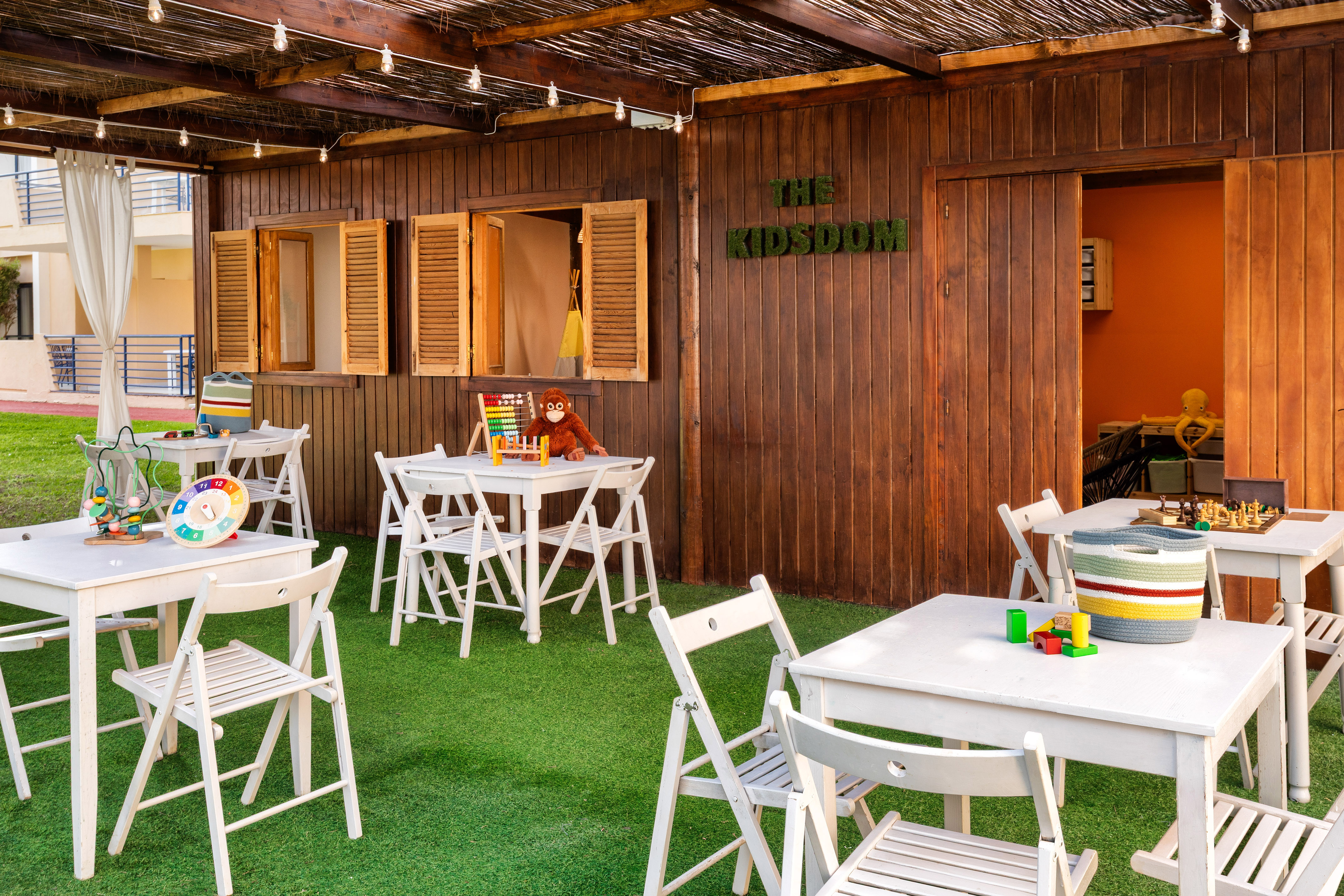 a small outdoor restaurant with white tables and chairs