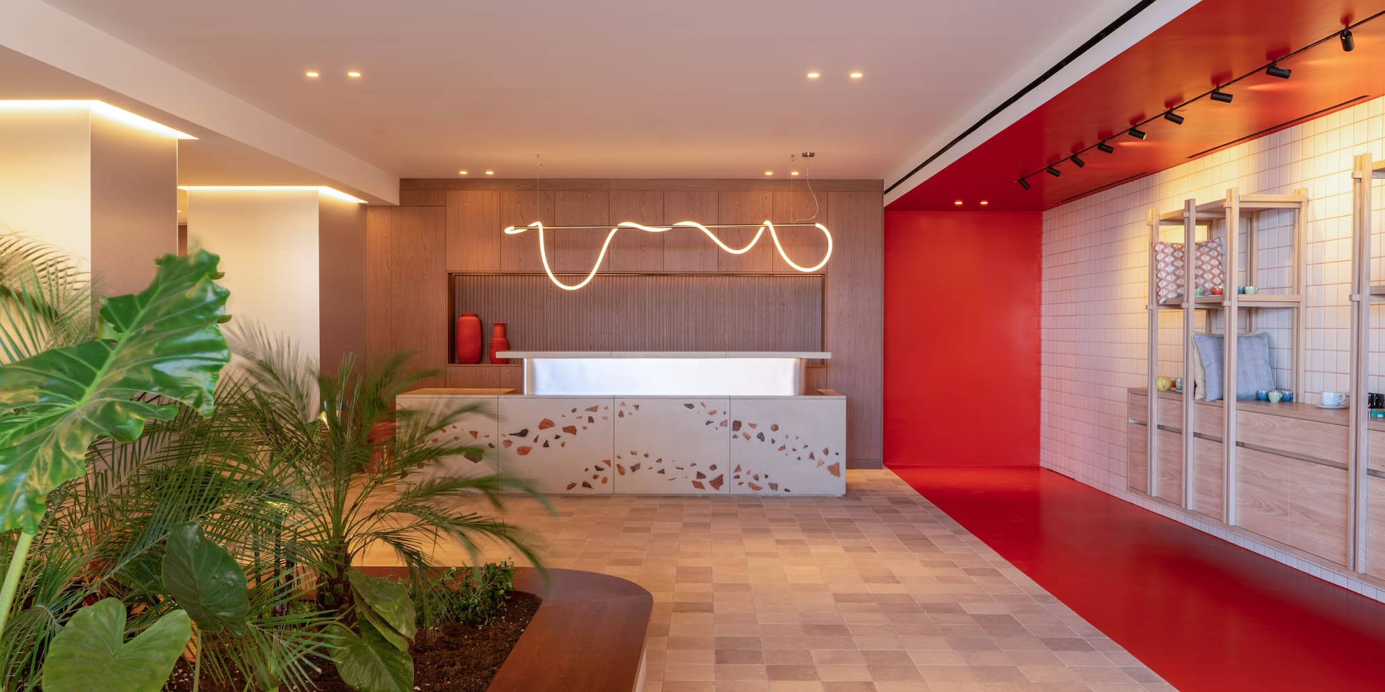 a room with a red wall and a white counter and plants