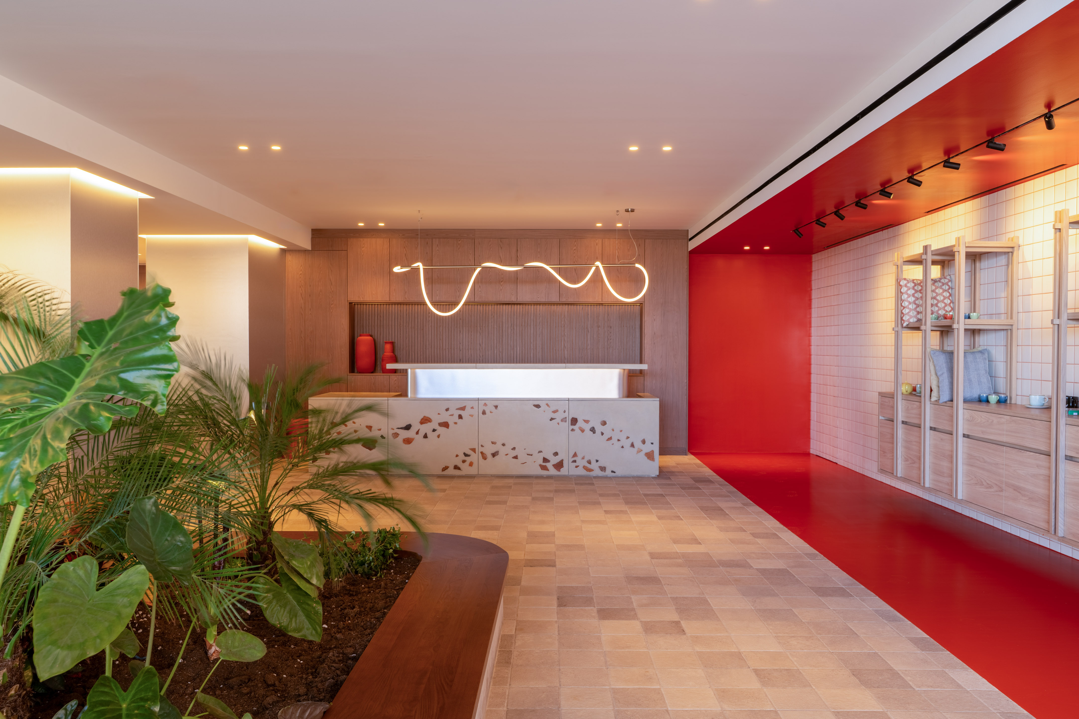 a room with a red wall and a white counter and plants