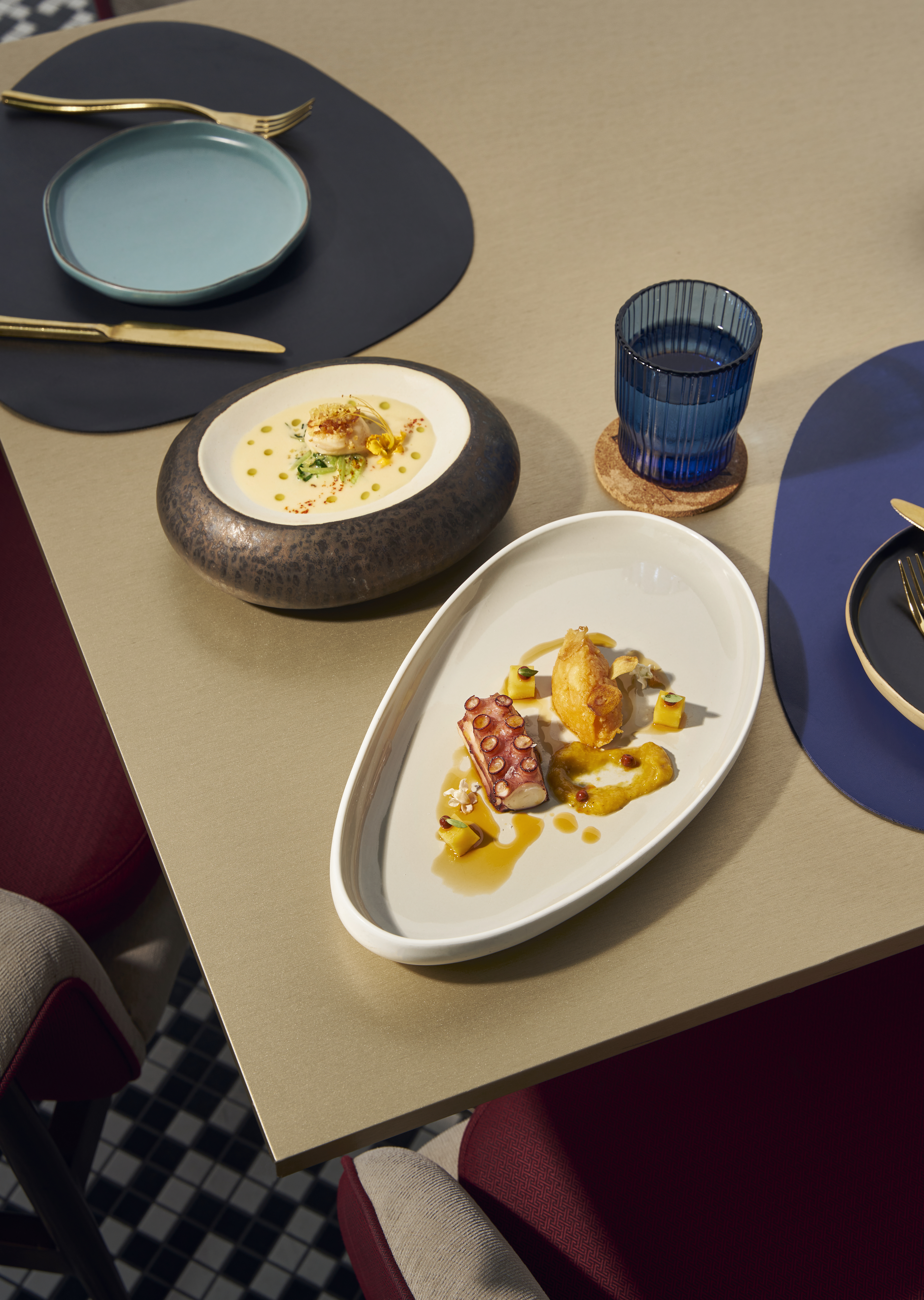 Gourmet octopus and creamy scallop dishes, elegant table setting.
