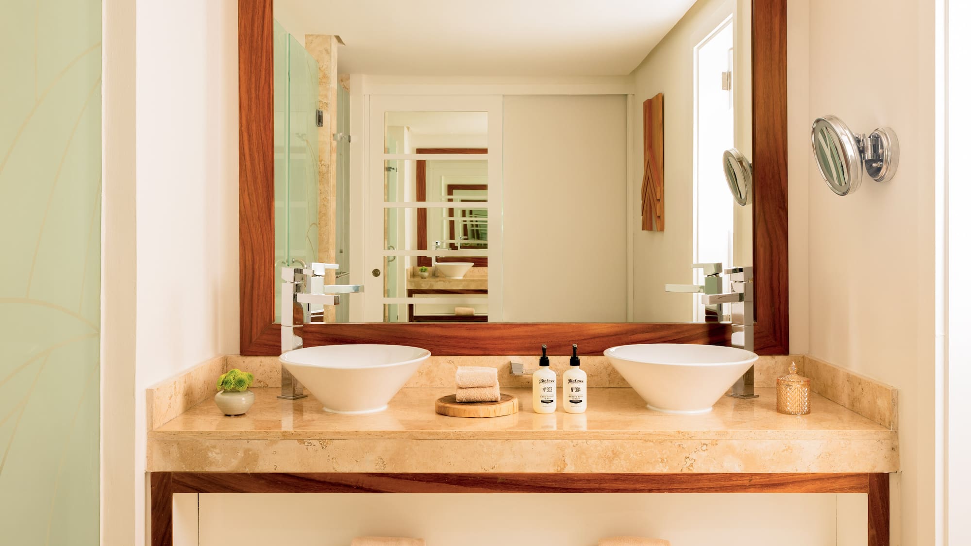 Modern double sink bathroom vanity with marble counter and wood-framed mirror.