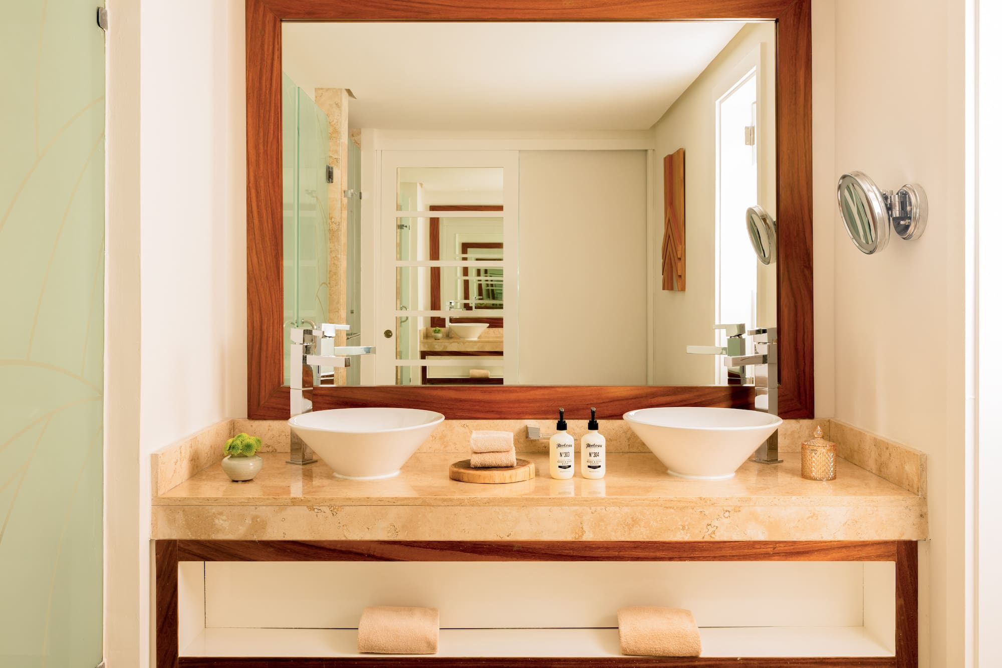 Modern double sink bathroom vanity with marble counter and wood-framed mirror.