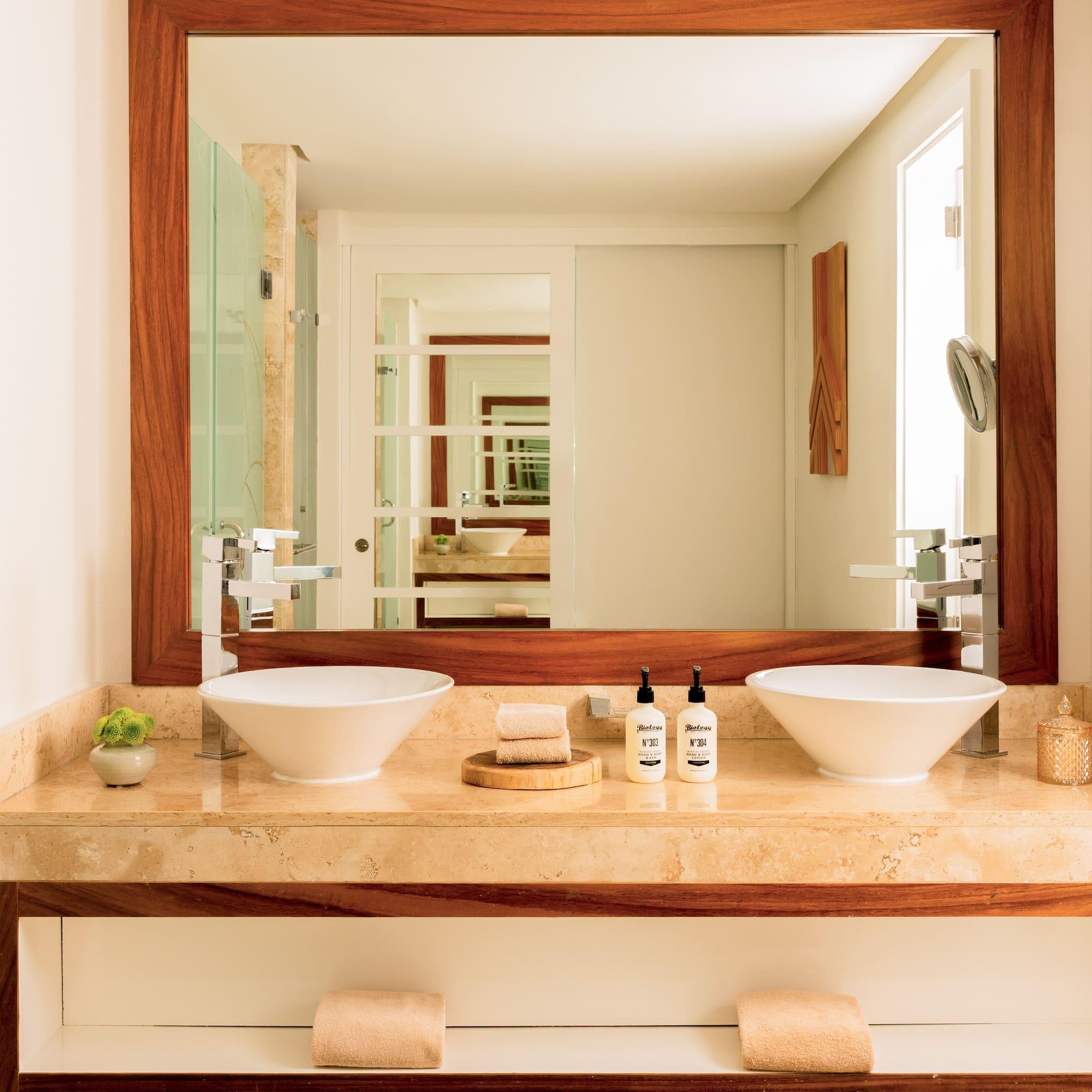 Modern double sink bathroom vanity with marble counter and wood-framed mirror.