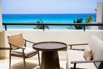 a table and chairs on a balcony overlooking the ocean