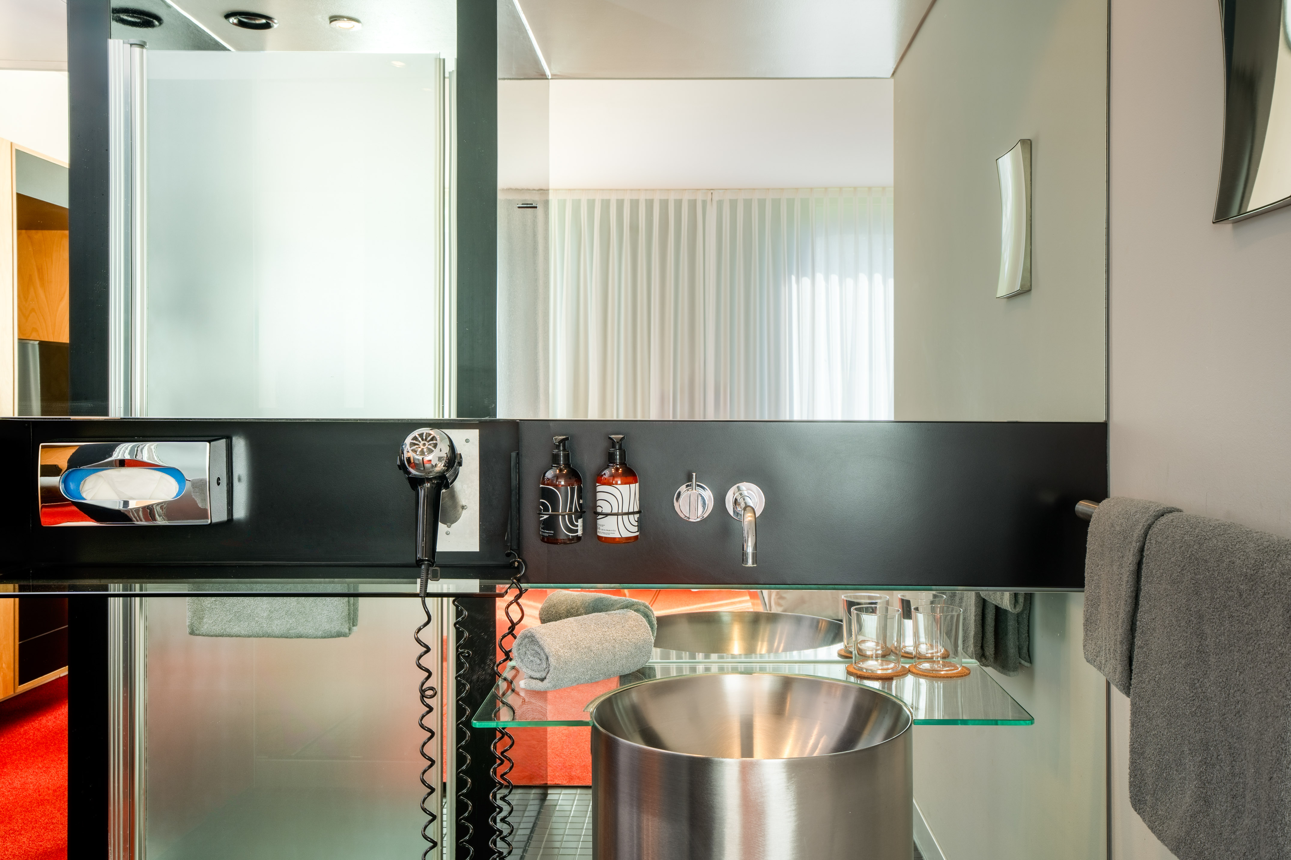Modern hotel bathroom vanity with stainless steel sink, mirror, toiletries, and towels. - The INNSiDE Premium Room - INNSiDE Düsseldorf Seestern, Düsseldorf