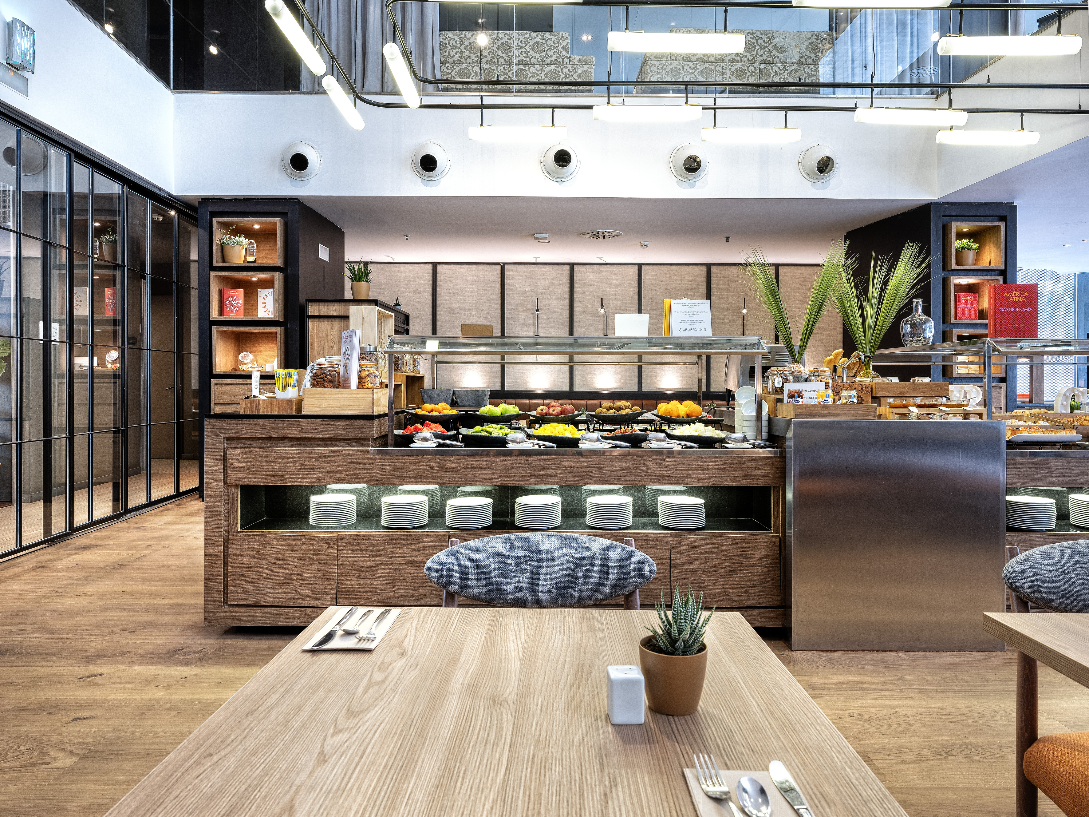 Modern hotel breakfast buffet with fresh fruit, pastries, and dining tables.