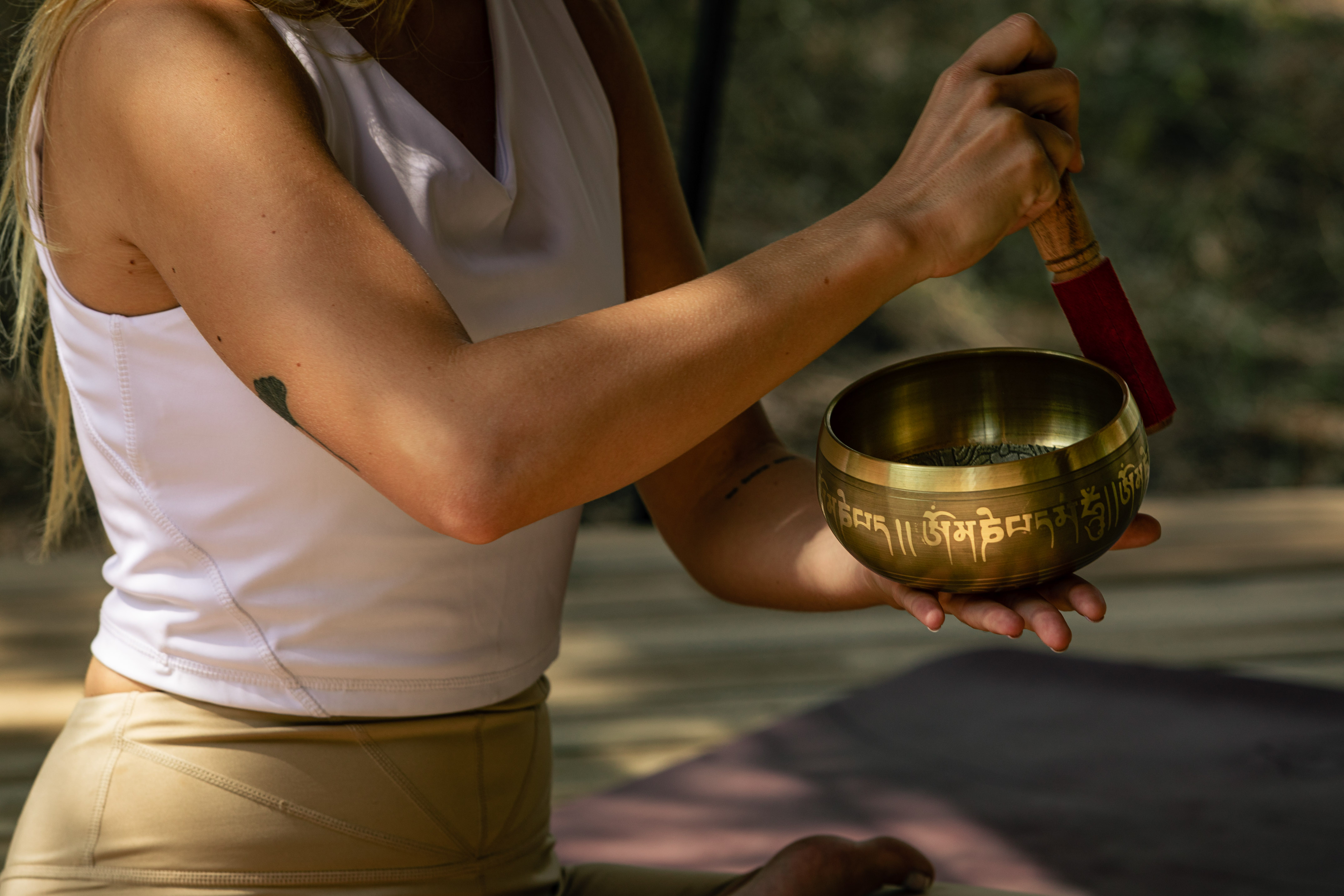 Woman holding a Tibetan singing bowl with a mallet, practicing meditation.