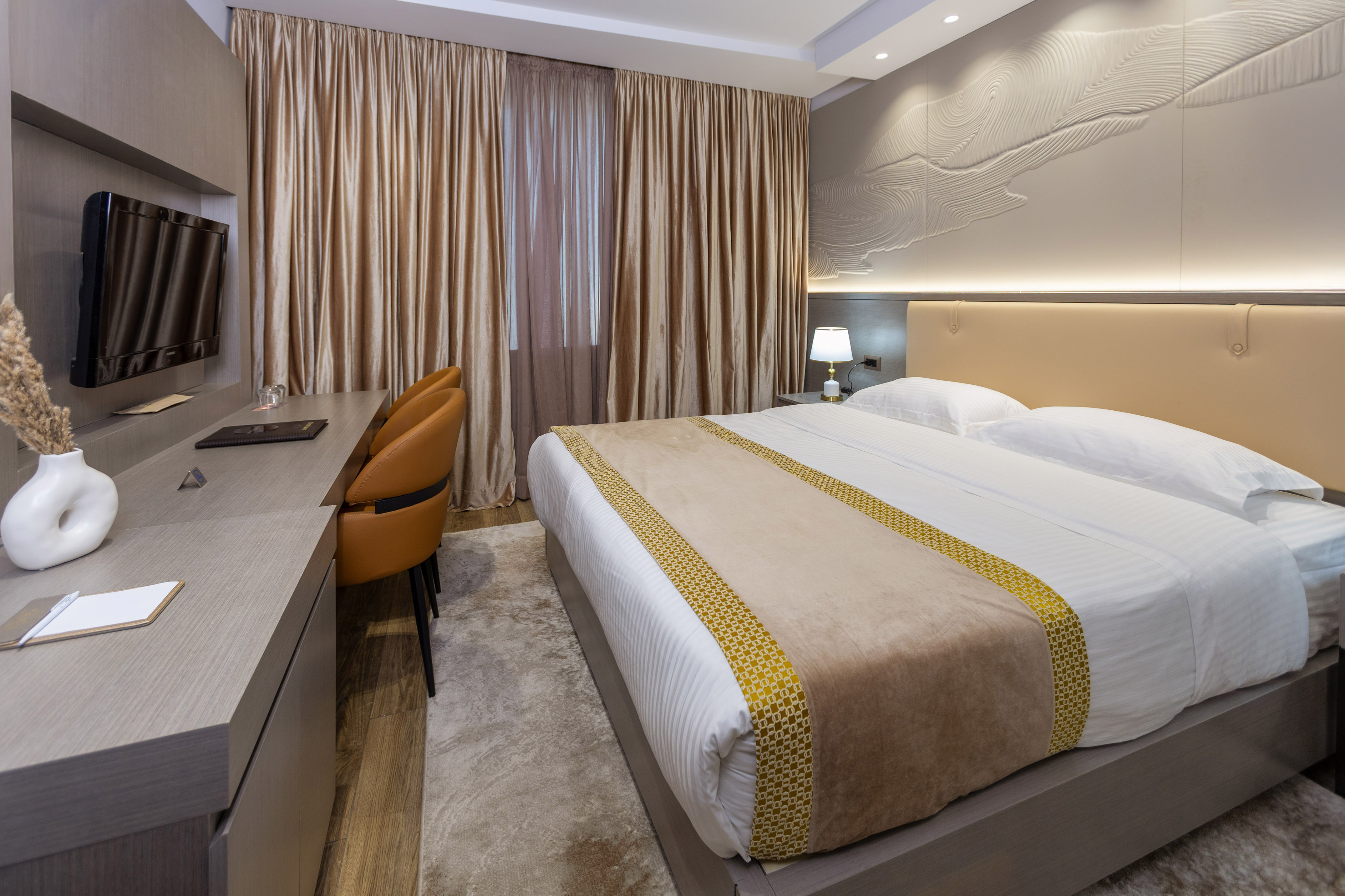 Modern hotel bedroom with king bed, work desk, and stylish decor.