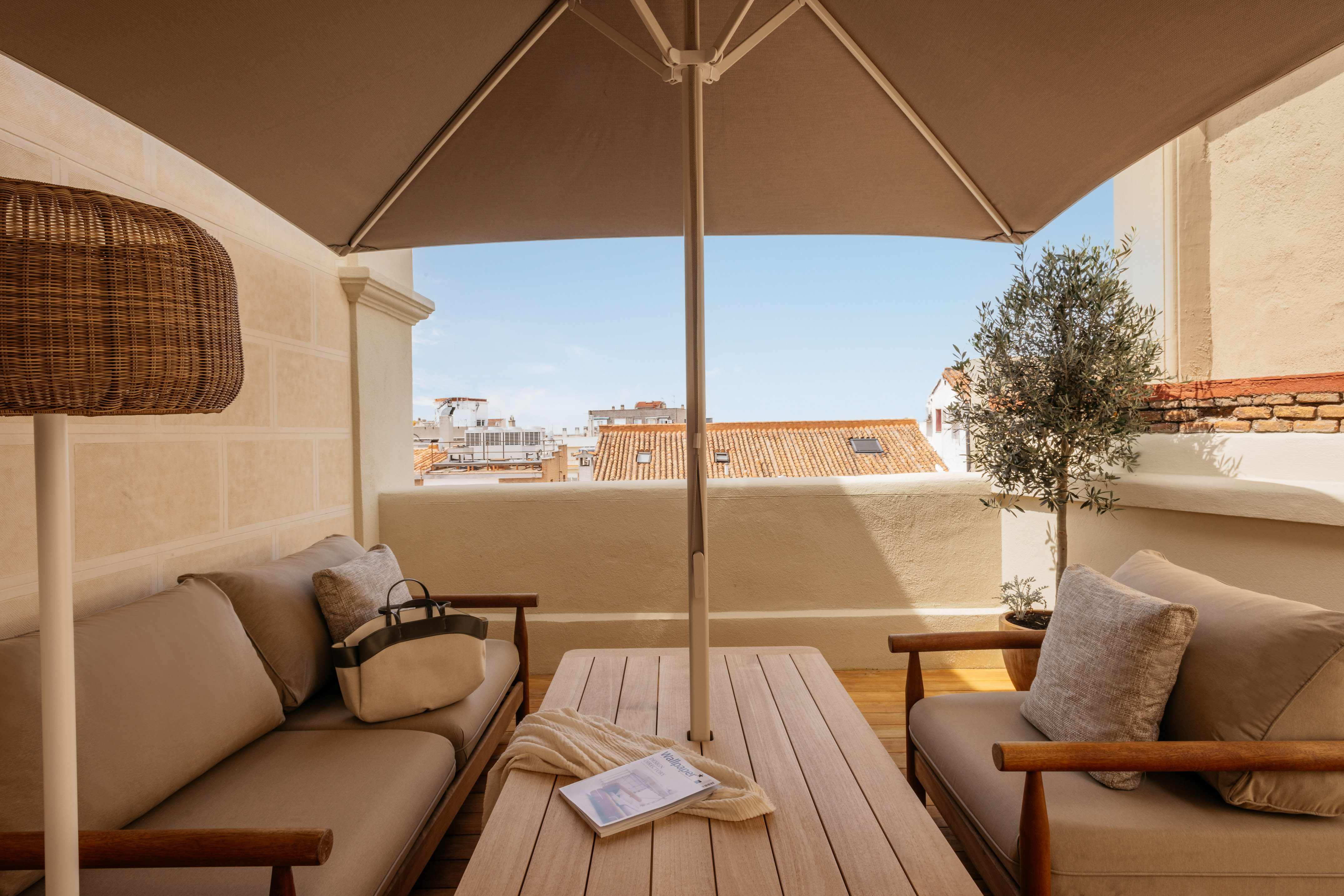 Rooftop terrace with outdoor lounge furniture, umbrella, and city views.