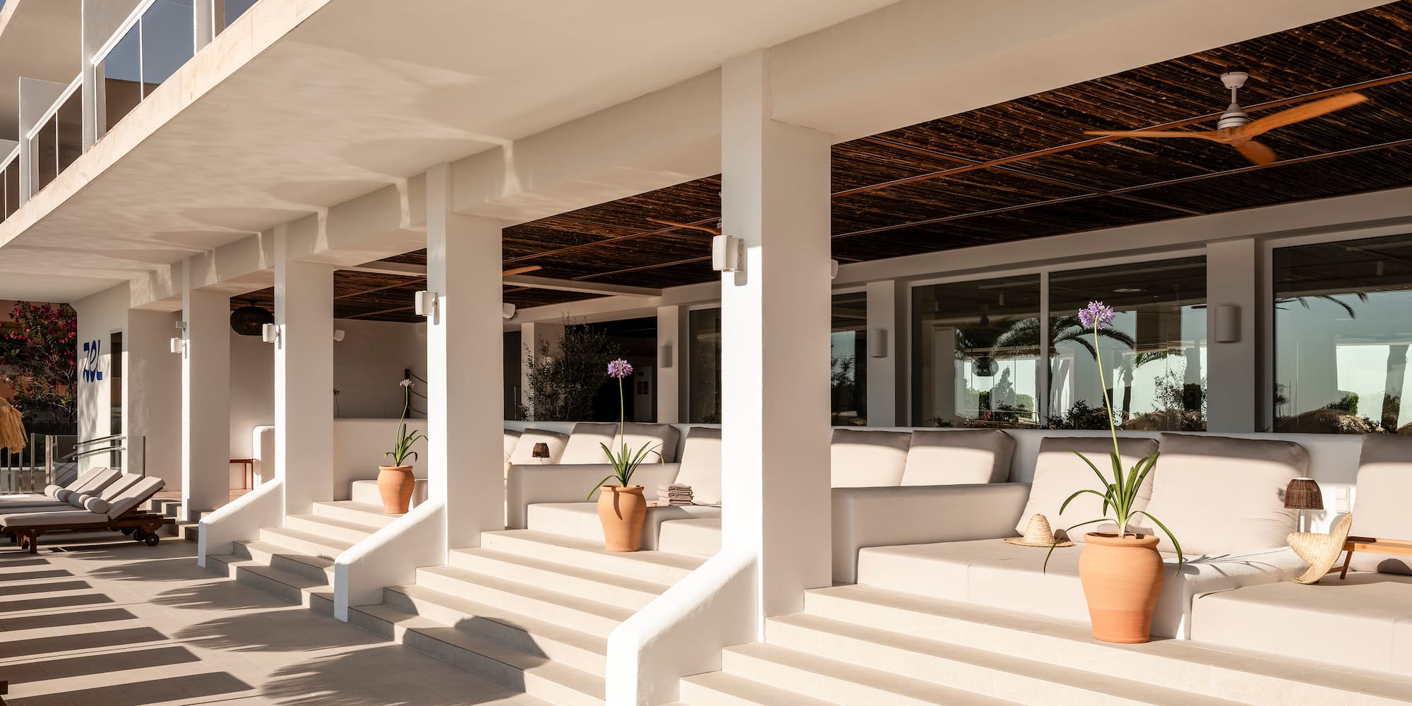 a white building with white pillars and a couch and potted plants