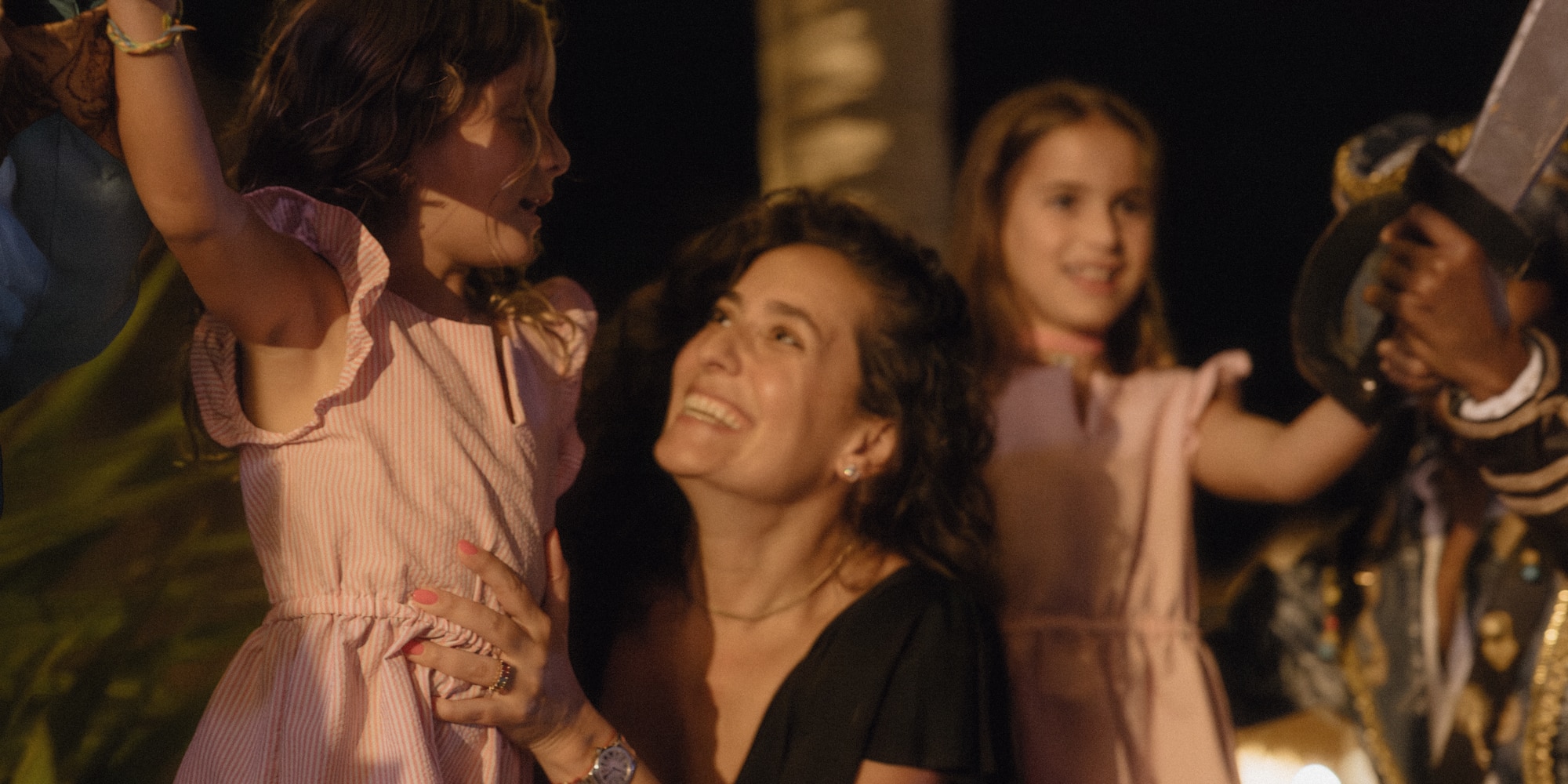 Smiling mom and two daughters enjoying a night event with a pirate performer.