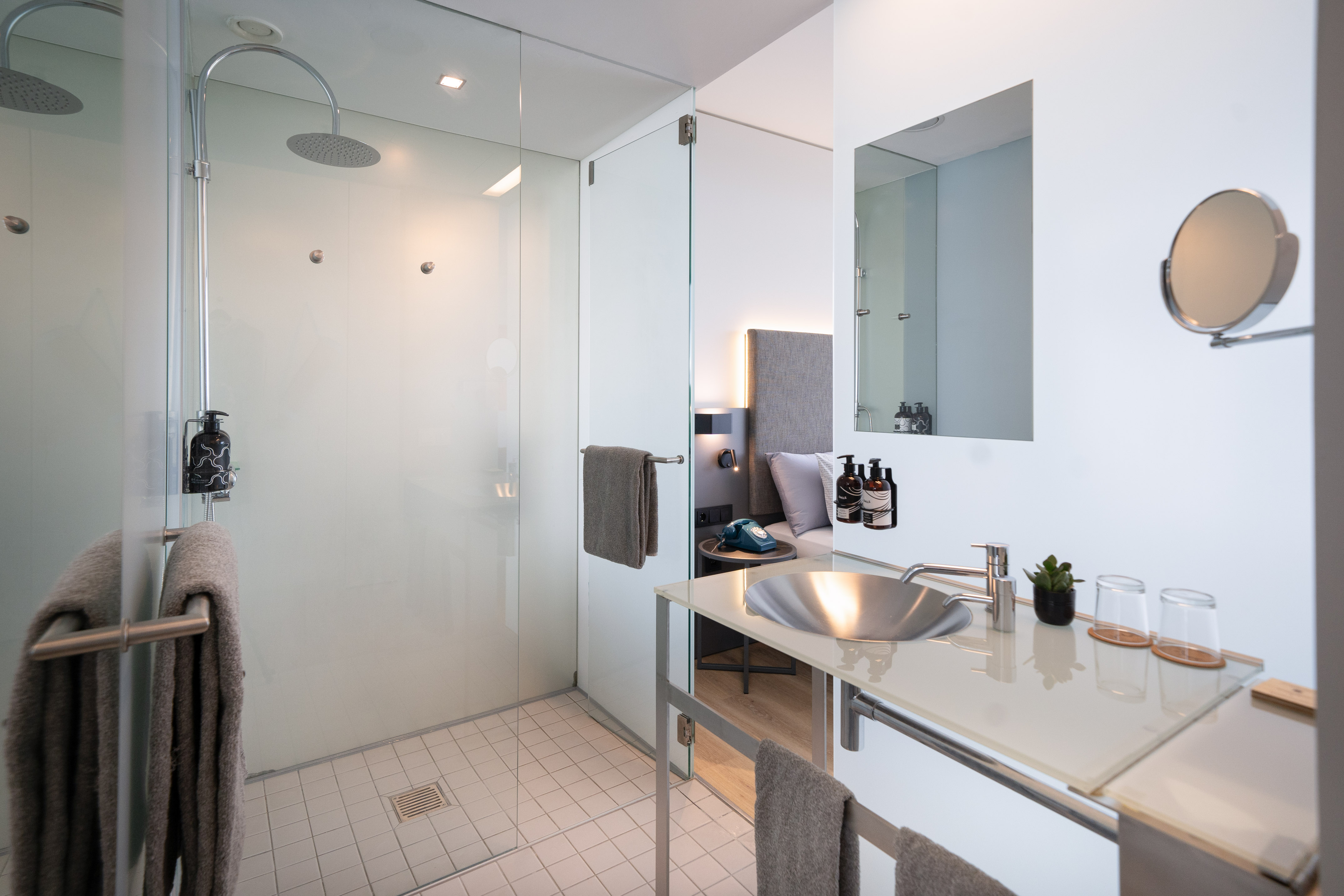 Modern hotel bathroom with walk-in glass rain shower and sleek vanity.