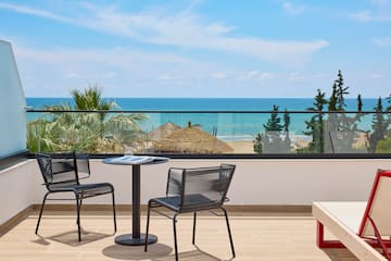 a table and chairs on a balcony overlooking the ocean
