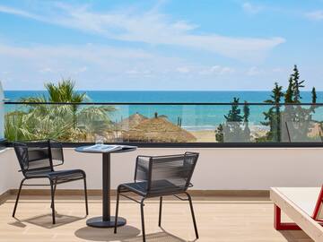 a table and chairs on a balcony overlooking the ocean