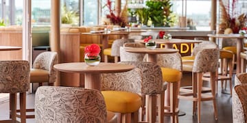 a group of tables with chairs and a red flower in a vase