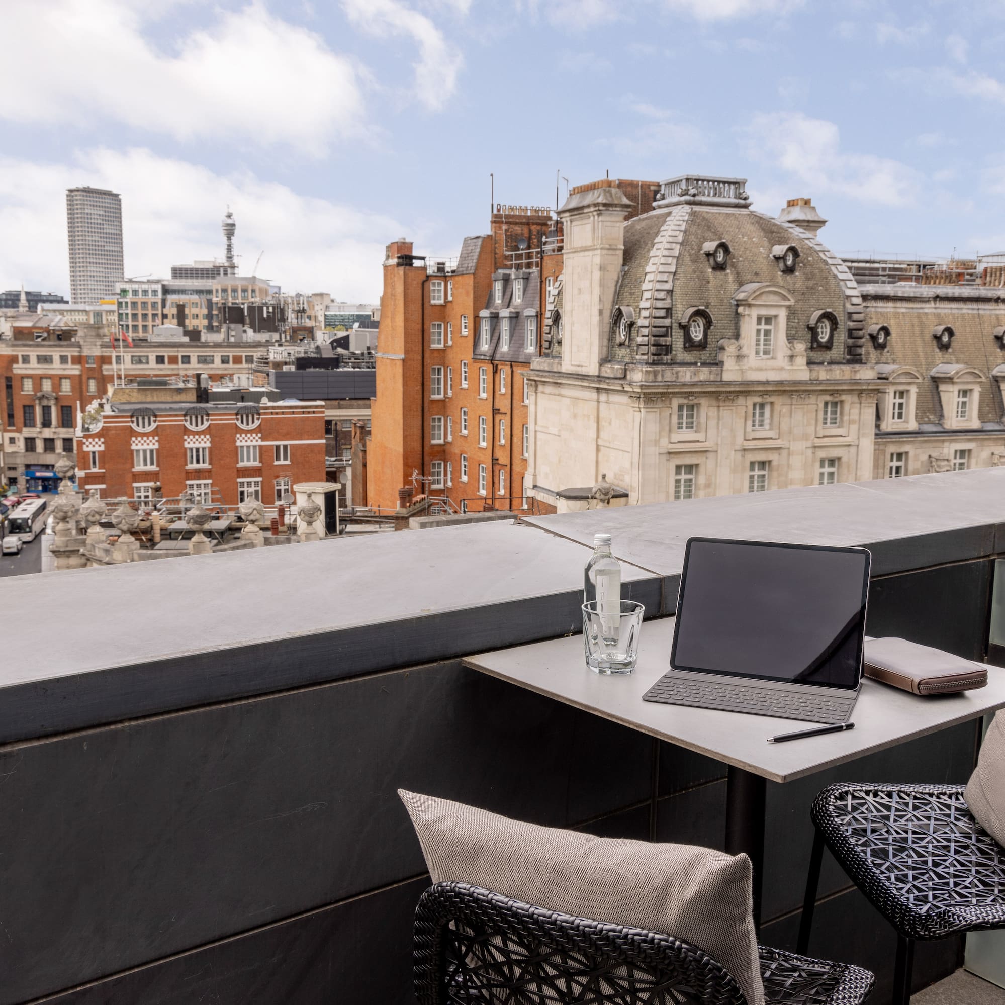 a laptop on a table with chairs and a glass bottle on it