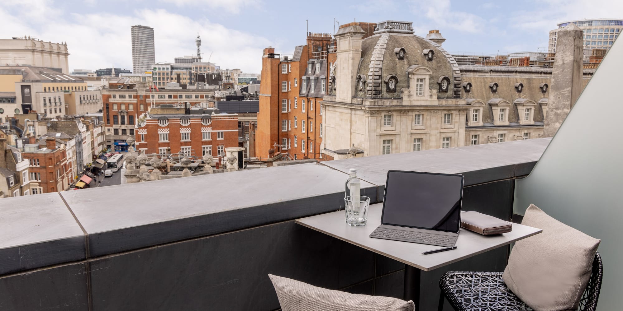 a laptop on a table with chairs and a glass bottle on it