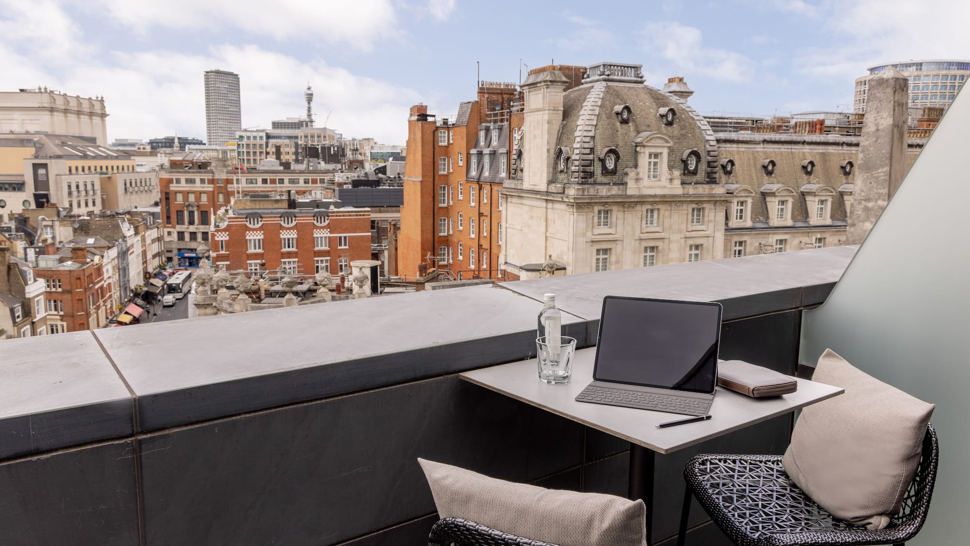 a laptop on a table with chairs and a glass bottle on it