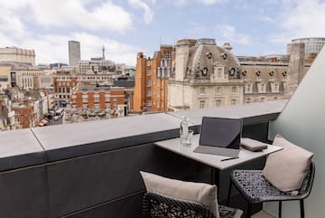 a laptop on a table with chairs and a glass bottle on it