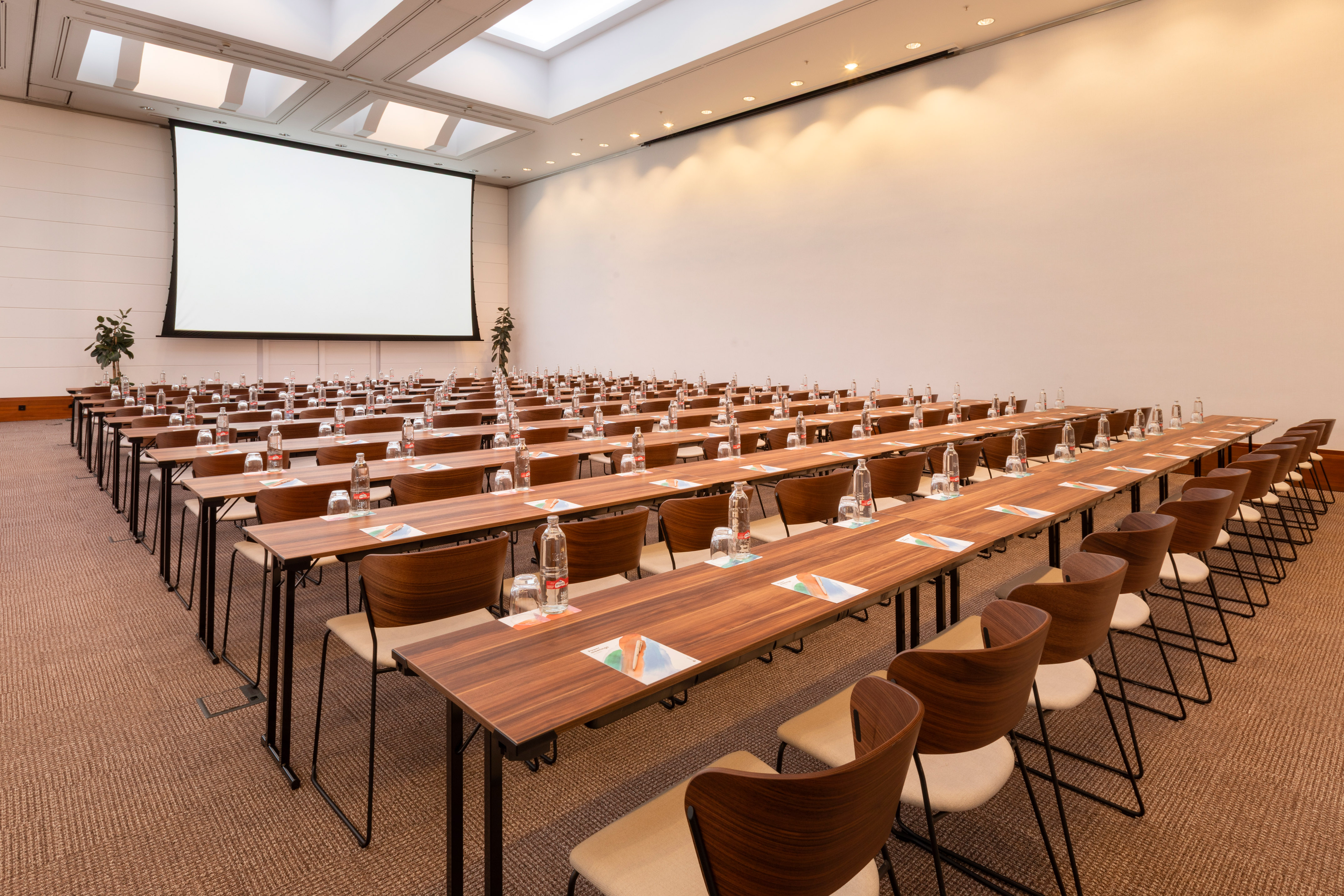 Conference room with tables, chairs, and a large projection screen.